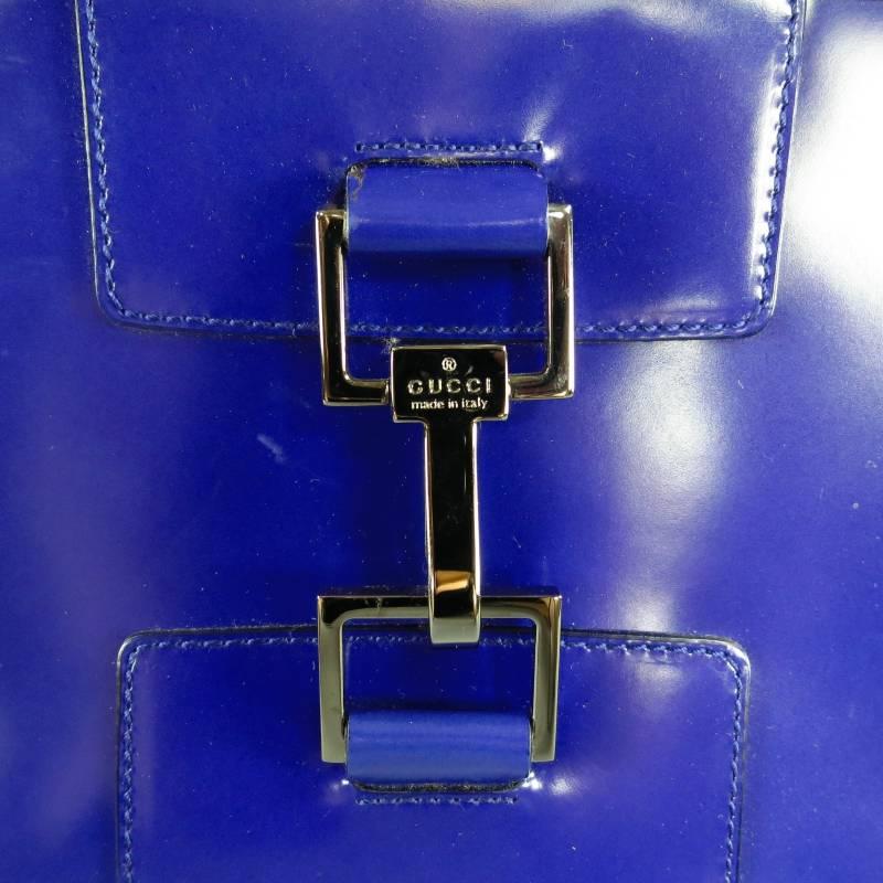 Fabulous shoulder bag by GUCCI. This rare piece comes in bold violet purple smooth semi matte structured patent leather and features silver tone square hardware, frontal embossed clasp detail, double top handles, zip closure, and internal zip
