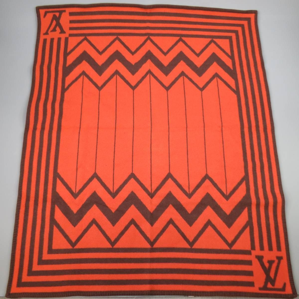 LOUIS VUITTON Karakoram Blanket scarf in a soft structured bold orange thick wool cashmere blend fabric with brown print throughout and embossed vachetta leather harness. Minor wear on harness. Made in Scotland
 
Excellent Pre-Owned Condition.
