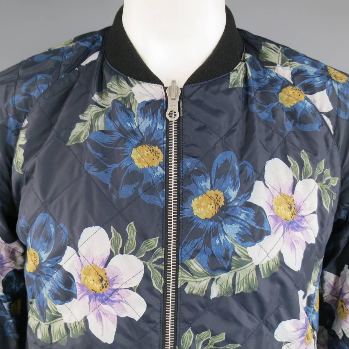 DRIES VAN NOTEN Jacket consists of cotton/ nylon blend material in a navy and black color tone. Designed in a reversible, zip-up front with side zipper pockets. Detailed in a quilted floral print throughout one side and solid black reversed. Rib
