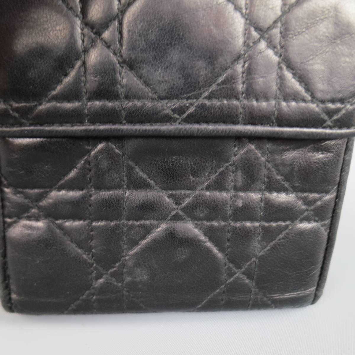 Vintage CHRISTIAN DIOR bi-fold wallet in signature Cannage embroidered soft black leather featuring a flap snap closure, back zip pouch with CD charm, and insternal card and money storage with red liner. Wear throughout. Made in Italy.
 
Good