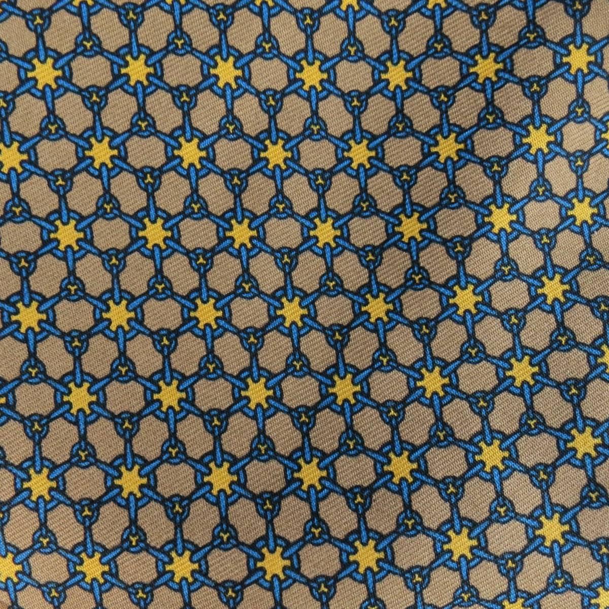 Vintage HERMES taupe silk twill ascot features a yellow star pattern amid interlocking blue rings for a pleasant geometric pattern. Made in France.
 
Fair Pre-Owned Condition. Stains throughout.
 
Measurements:
 
Length: 45 In.
Width: 6.65 in.

