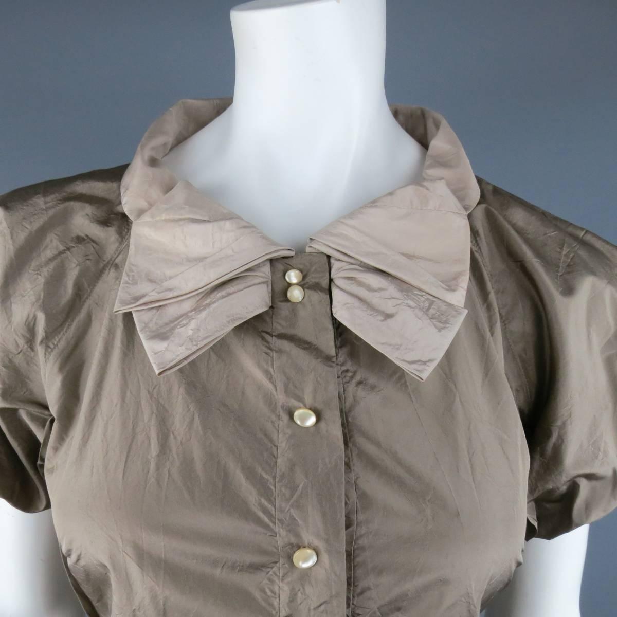 MARC JACOBS taupe silk blouse features gathered balloon sleeves, bow detail around the collar with hook and eye closure, and snap closure with mock buttons. Made in USA.
 
Excellent Pre-Owned Condition.
Marked: 8
 
Measurements:
 
Shoulders: 21