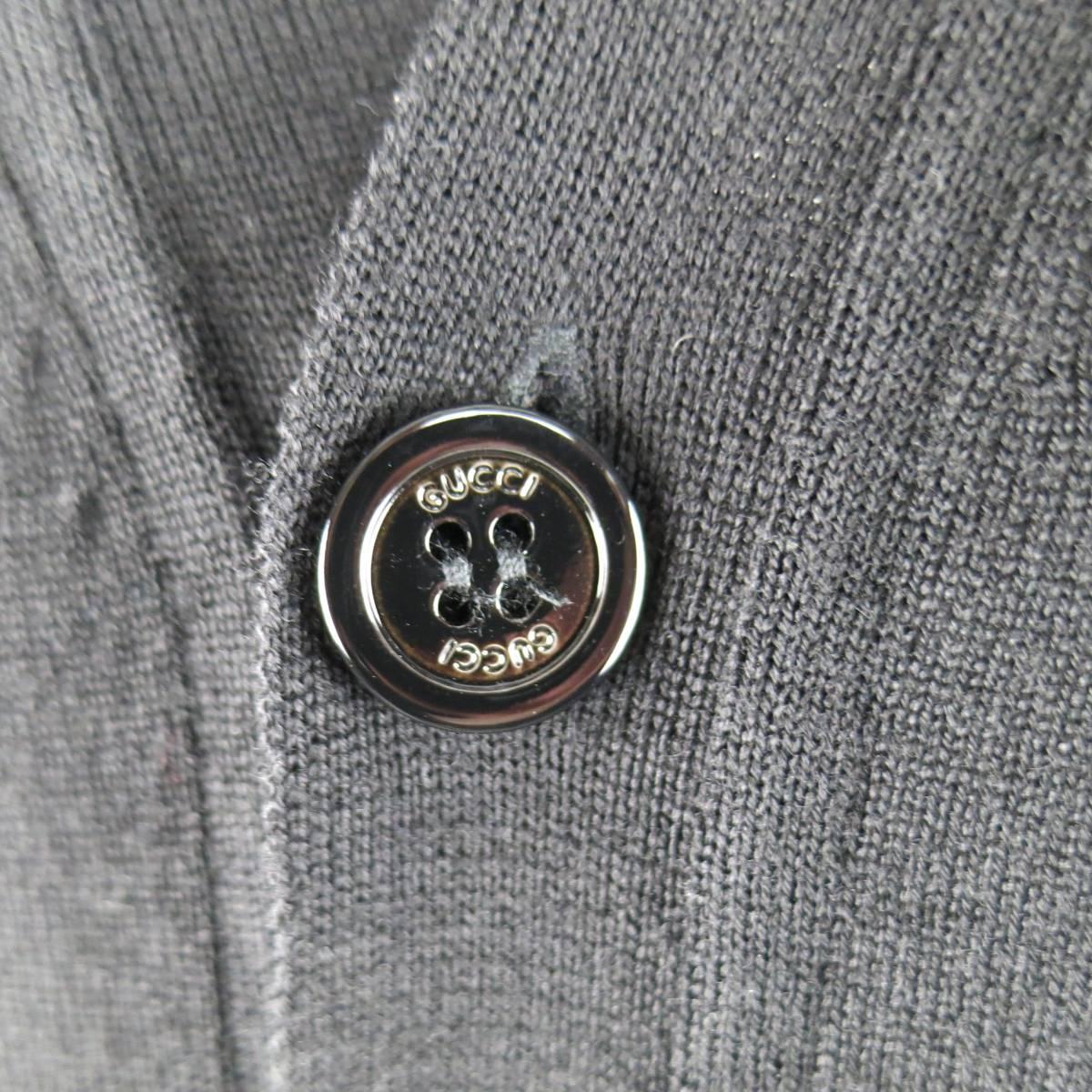 Basic GUCCI button up V neck cardigan in a light weight black wool knit with raglan sleeve detail and ribbed cuffs and hem. Made in Italy.
 
Good Pre-Owned Condition
Marked Size: L
 
Measurements
 
Shoulders: 18 in.
Sleeve: 25 in.
Chest: 40