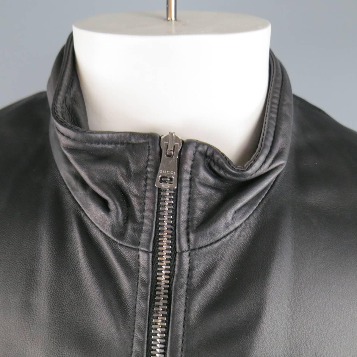 GUCCI tailored bomber jacket in a soft matte black leather featuring a high collar, silver tone zip closure, slit pockets, embossed sleeve logo, and stretch band hems with internal stripe detail. Wear throughout bands. Made in Italy.
 
Good