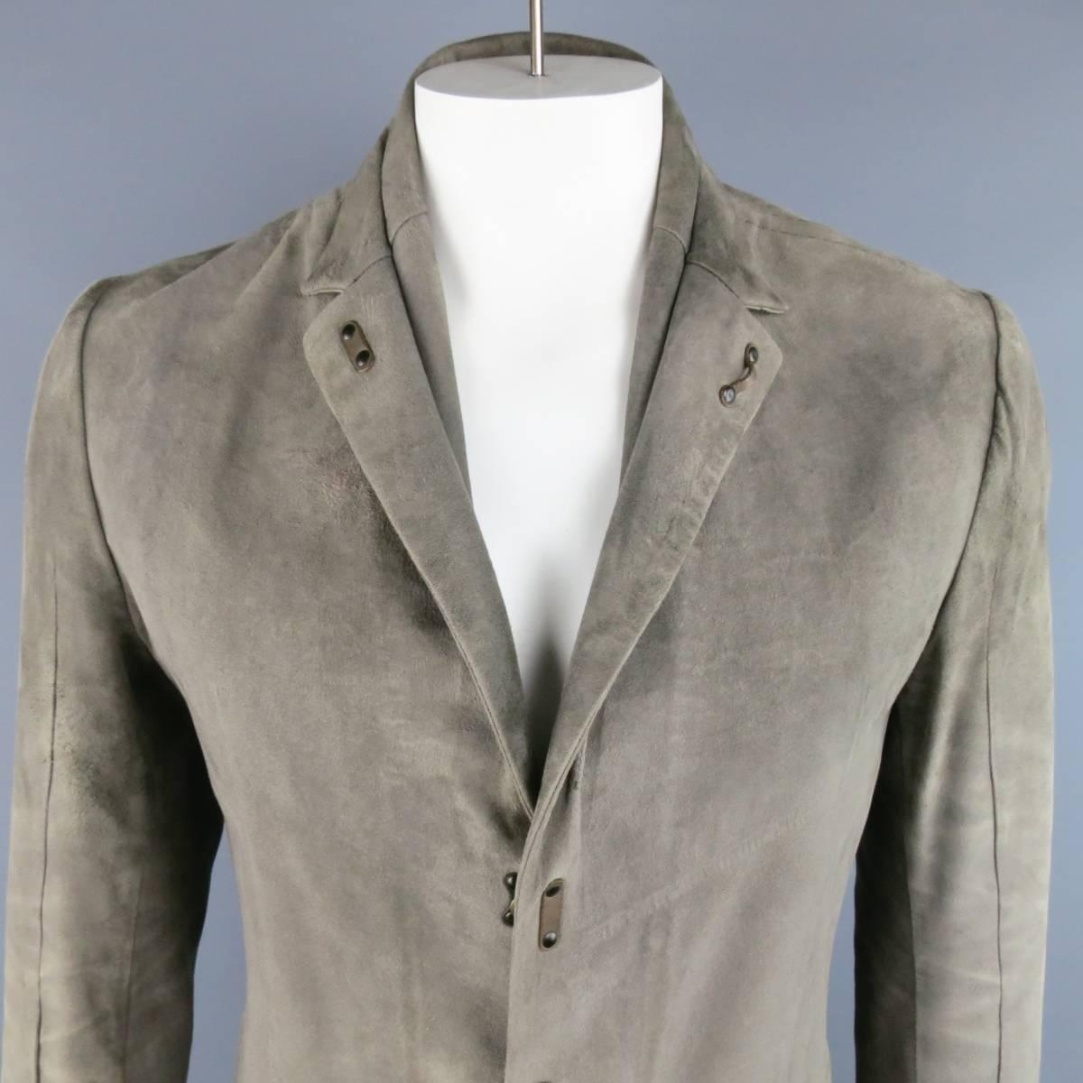 ISAAC SELLAM sport coat style jacket in a light taupe gray suede featuring a notch lapel with leather hook eye closure and underseam detail, triple hook eye closure, hook eye cuffs. Wear throughout. Made in Italy.
 
Good Pre-Owned Condition. Retails