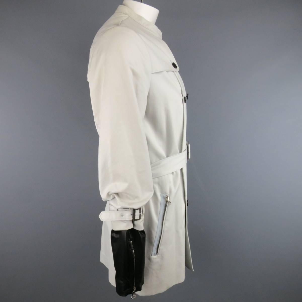 This unique 3.1 PHILLIP LIM trench coat comes in a light khaki cotton twill and features a band collar with hook eye closure, double breasted button closure, storm flap detail, slanted zip pockets, belted waist, and detachable leather zip biker