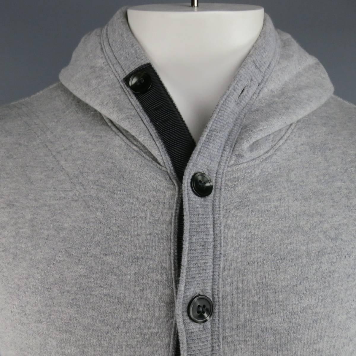 THOM BROWNE hoodie in a heather gray, quilted French terry featuring a button up closure with charcoal ribbon trim, pouch pocket with patch, ribbed piping trim throughout, and 4 bar four white stripes at the left sleeve. Made in Japan.
 
Excellent