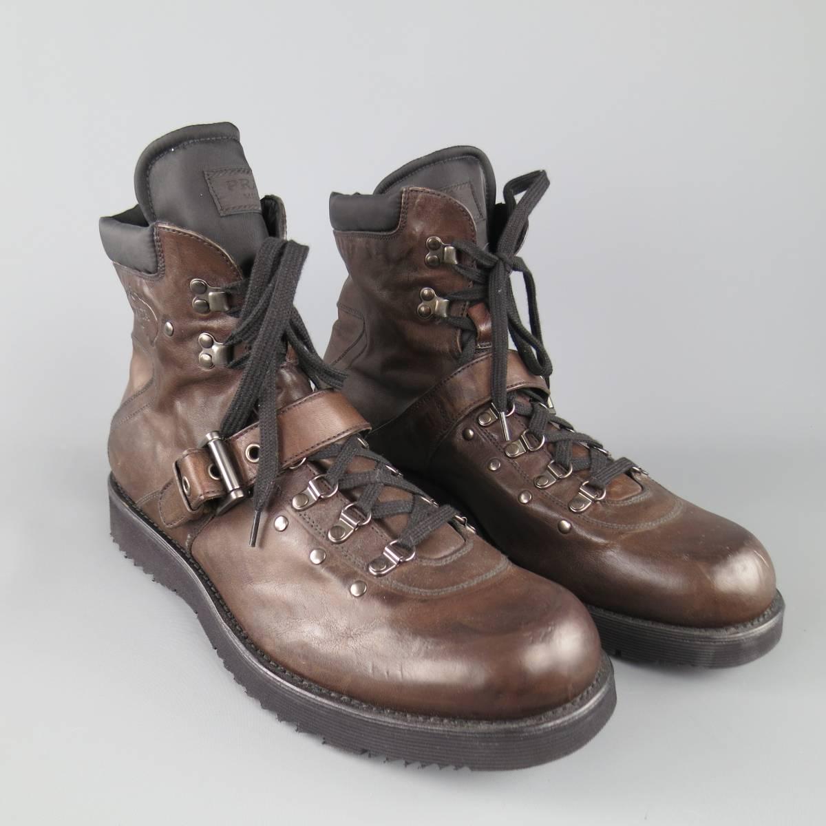 PRADA hiking style boots in a chocolate brown leather featuring dark silver tone sky hooks, strap with buckle, thick rubber sole, and black nylon ankle and tongue. Made in Italy.
 
Excellent Pre-Owned Condition.
Marked: UK 12
 
Outsole: 13 x 5