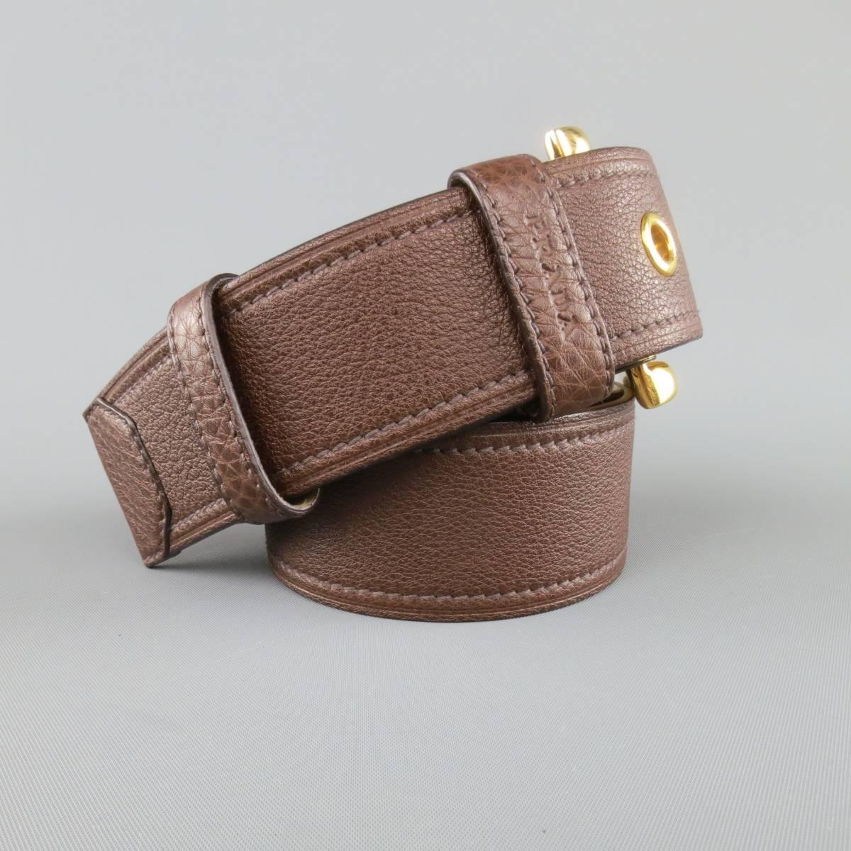This PRADA belt features a rich brown textured leather strap with gold tone buckle and grommets. Made in Italy.
 
Excellent Pre-Owned Condition.
Marked: 32/80
 
Length: 41 in.
Width: 1.65 in.
Fits: 30-34 in.
Buckle: 2.5 x 2.45 in.
