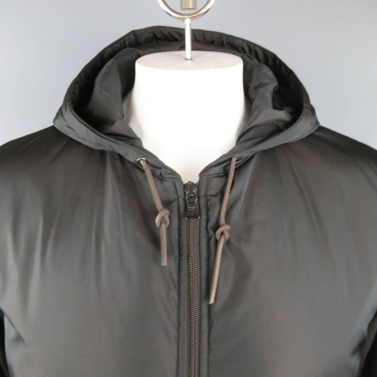 Classic PRADA jacket in a iridescent brown sport fabric featuring a zip up front, slanted zip pockets, drawstring hood with leather pulls, charcoal knit cuffs, under arm slits, and leather elbow patches. Made in Italy.
 
Excellent Pre-Owned