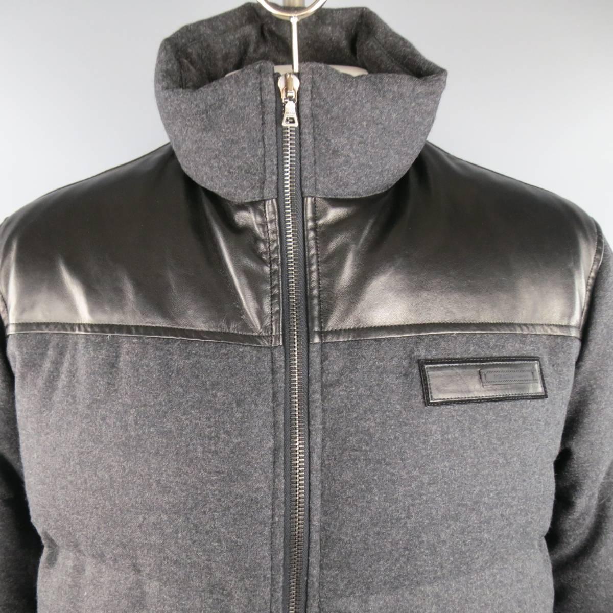 PRADA puffer coat in a charcoal gray quilted down filled wool featuring a black leather top panel, high collar with optional hood, snap pockets, and leather logo patch. Made in Italy.
 
Excellent Pre-Owned Condition.
Marked: XL
 
Measurements:
