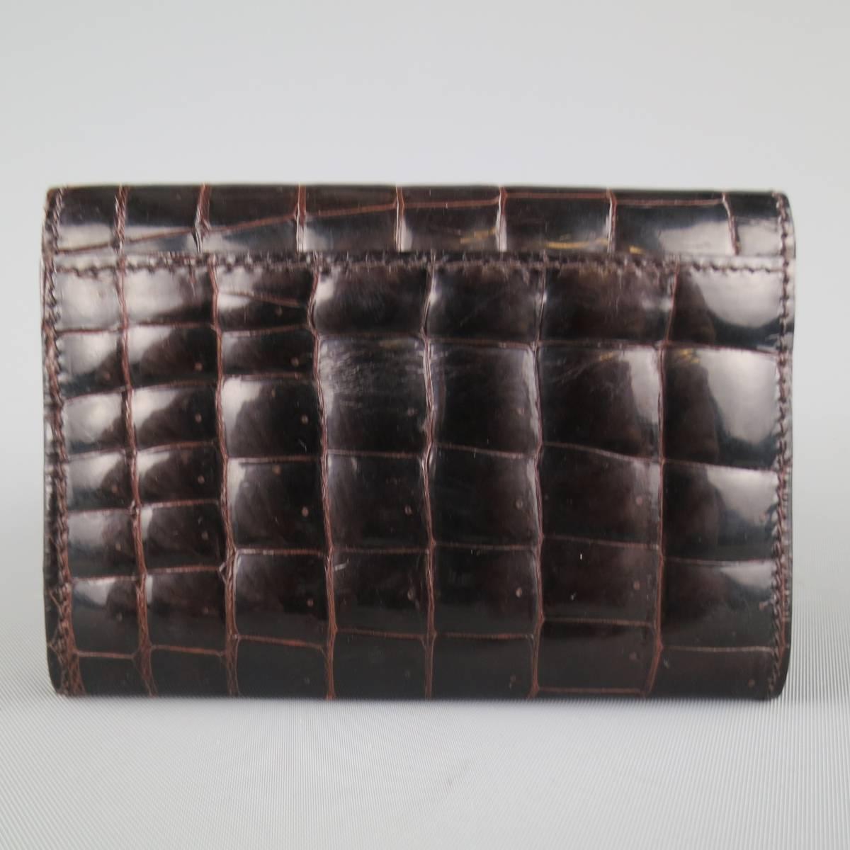 BOTTEGA VENETA card hold wallet in a chocolate brown high shine alligator crocodile textured leather featuring a snap flap closure. With dust bag. Made in Italy.
 
Good Pre-Owned Condition.
 
4.25 x 3 in.


Web ID: 80794 
