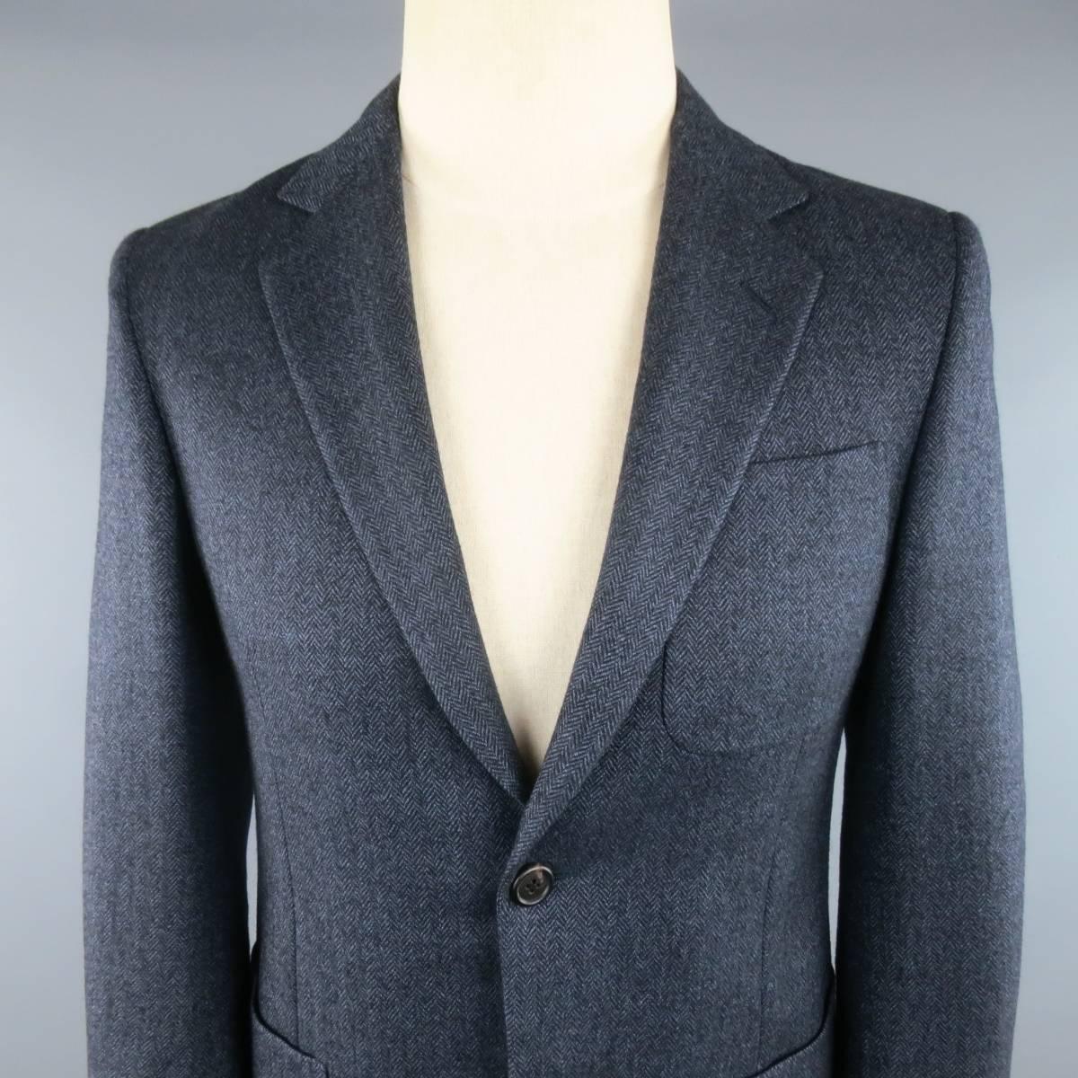 PRADA sport coat comes in a muted ash blue herringbone wool and features a notch lapel, two button closure, triple patch pockets. and functional button cuff sleeves. Made in Italy. Retails at $2440.00.
 
Excellent Pre-Owned Condition.
Marked: IT