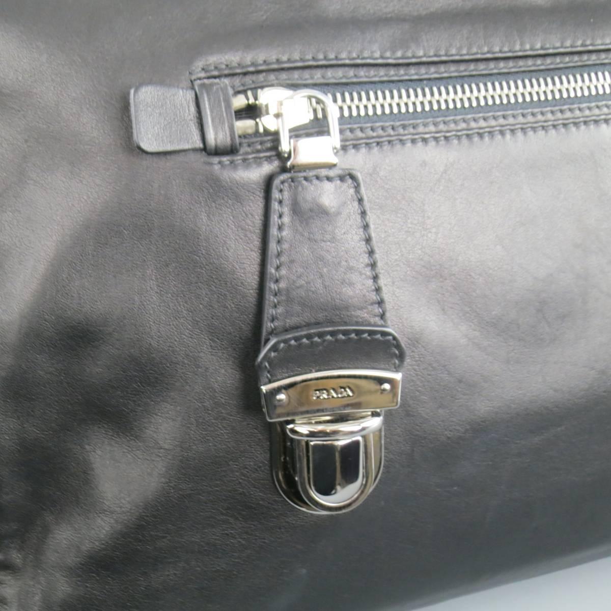 PRADA handbag in black smooth leather featuring a frontal zip pocket with silver tone snap tab, side hardware with optional shoulder strap, side logo plaque, and double covered top handles. Made in Italy. AD 2010.
 
Good Pre-Owned Condition.
