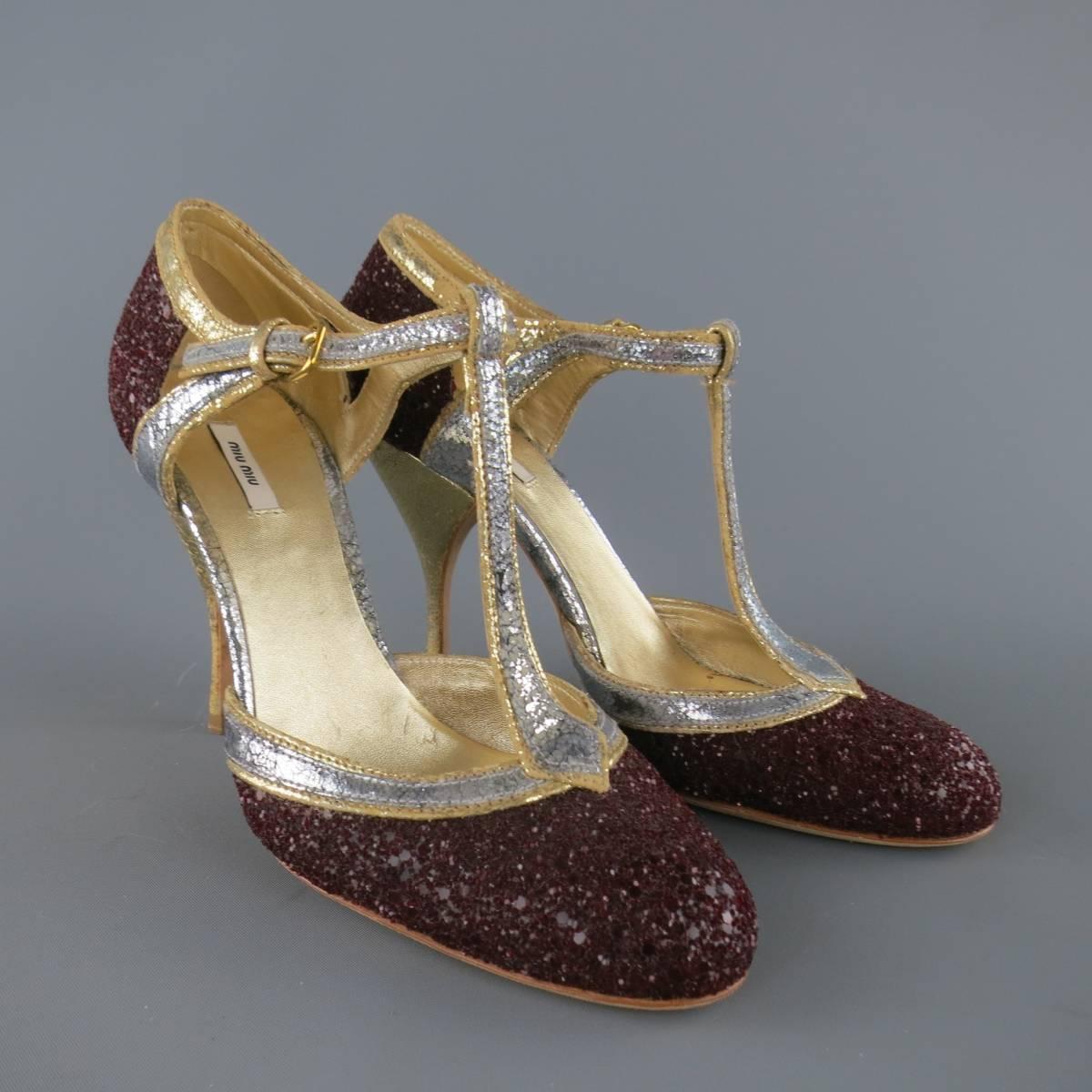 These fabulous MIU MIU pumps come in burgundy glitter encrusted leather and feature metallic textured gold and silver piping, a T strap ankle harness, and gold crackle foil heel. Minor wear throughout. Made in Italy.
 
Good Pre-Owned