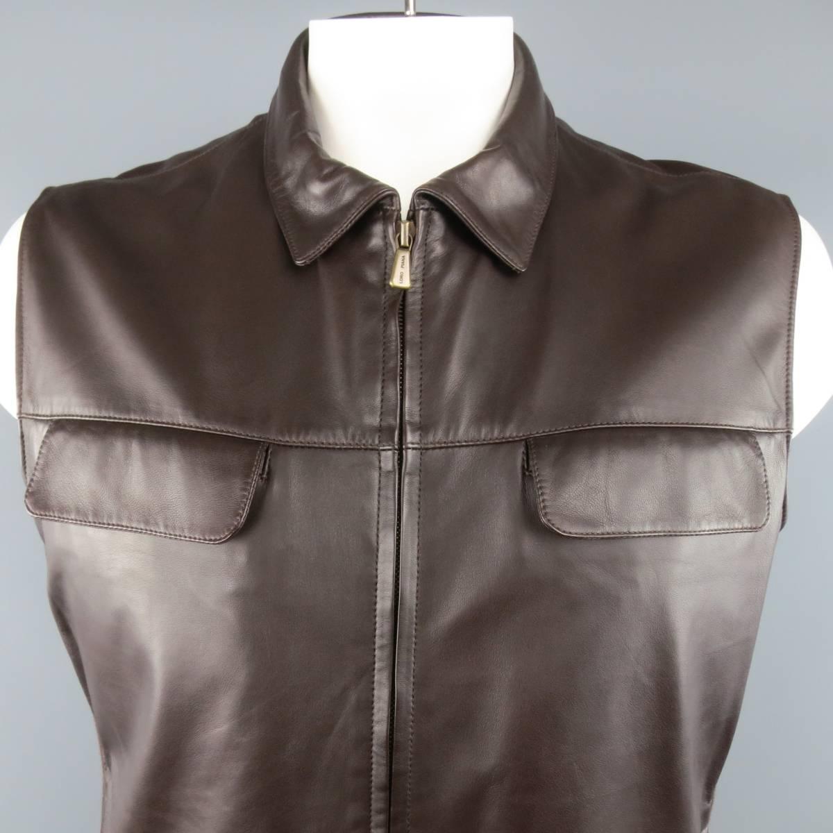 LORO PIANA vest comes in rich chocolate brown smooth leather and features a pointed collar, dark gold tone double zip front, double flap chest pockets, slit side pockets, and ribbed knit side panels. Made in Italy.
 
New with Tags.
Marked: XL
