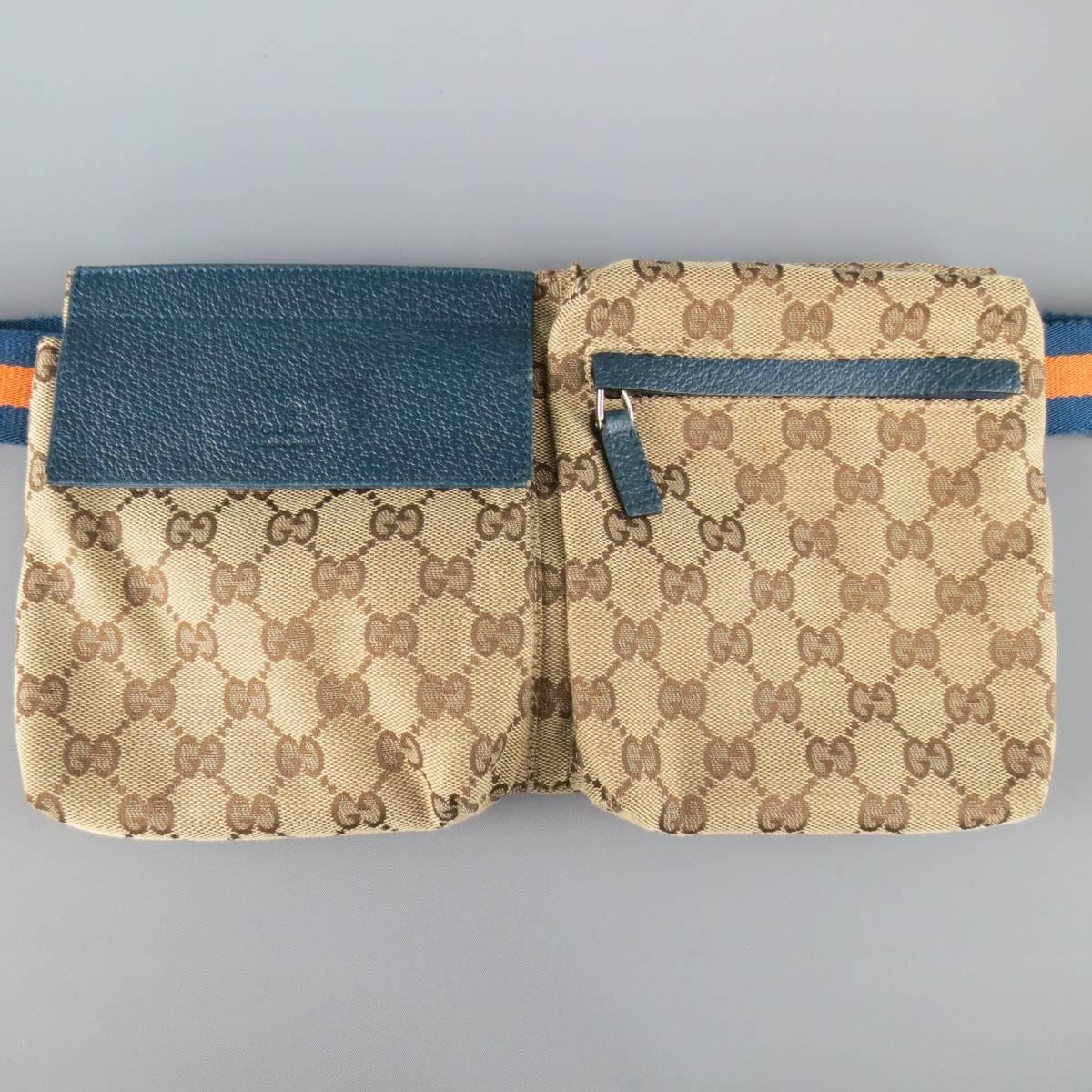 Rare GUCCI fanny pack comes in signature beige and brown Guccissima monogram print canvas and features two pouches with navy blue textured leather details and orange and navy adjustable webbing strap with silver tone engraved buckle. Wear