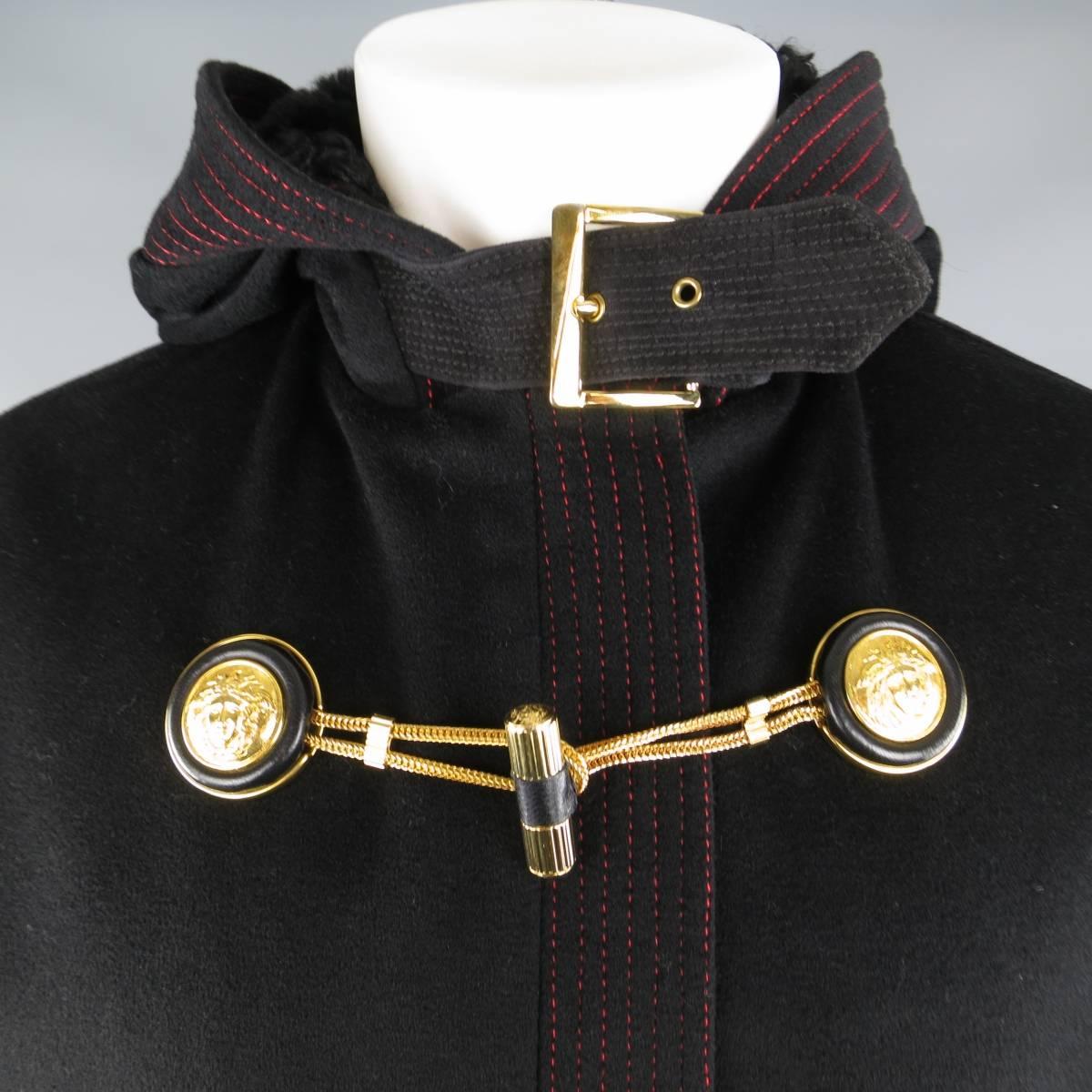 This fabulous vintage 1990's GIANNI VERSACE COUTURE coat comes in a black wool felt with bold red contrast stitching throughout and features a hidden placket zip front, hood with faux lamb fur liner and belt, faux fur cuffs with suede piping,