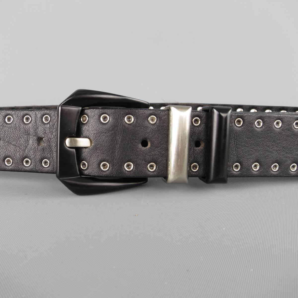 Vintage 1990's GIANNI VERSACE statement belt features a black leather small grommet studded strap with silver tone Medusa studs, matte black metal Western buckle, and silver tone metal cutout panels with black Medusa motifs. Made in Italy.
