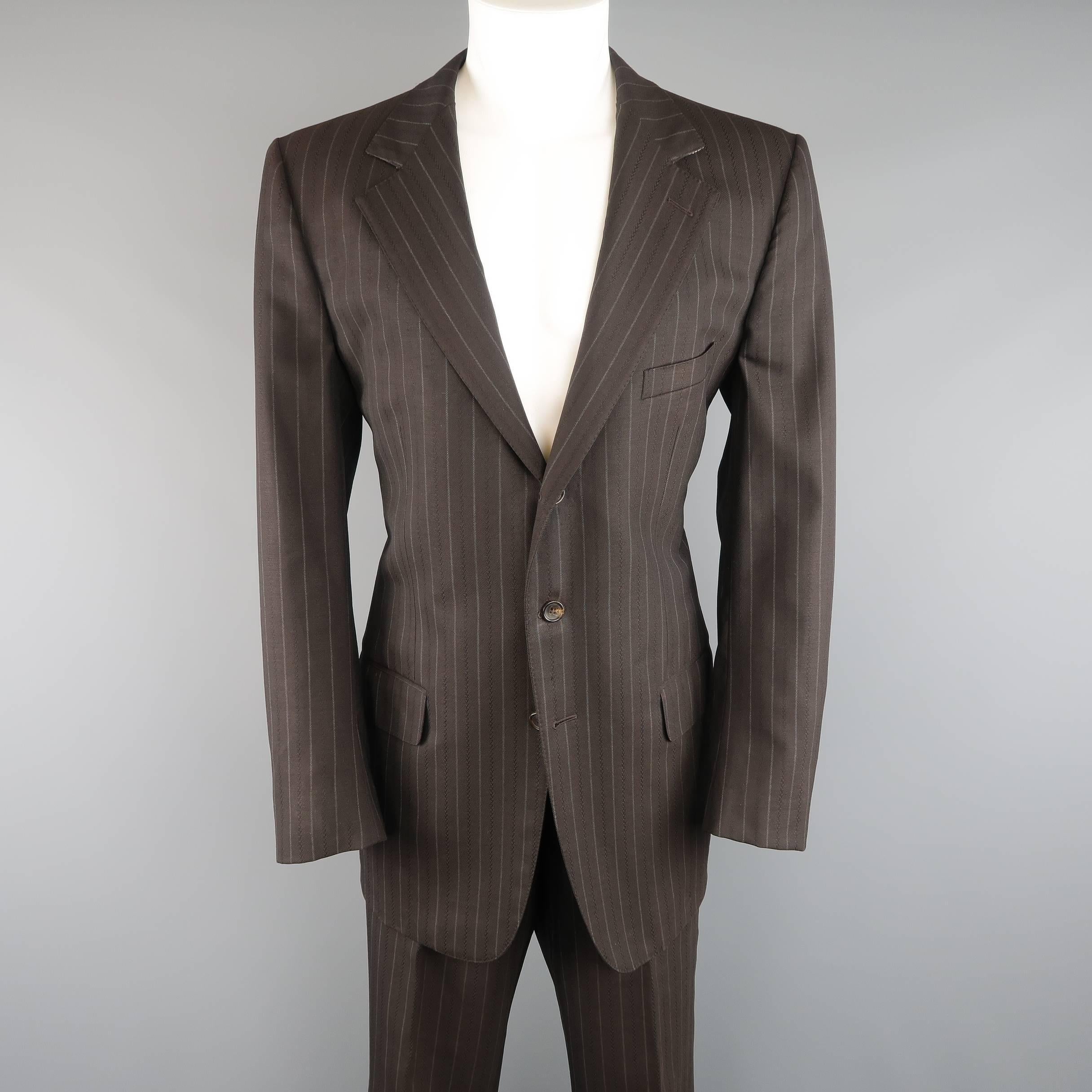 GUCCI by TOM FORD suit comes in a rich chocolate brown chalk stripe wool twill with tonal stripe texture and includes a three button, wide notch lapel sport coat and matching flat front trousers. Minor wear throughout. Made in Italy.
 
Good