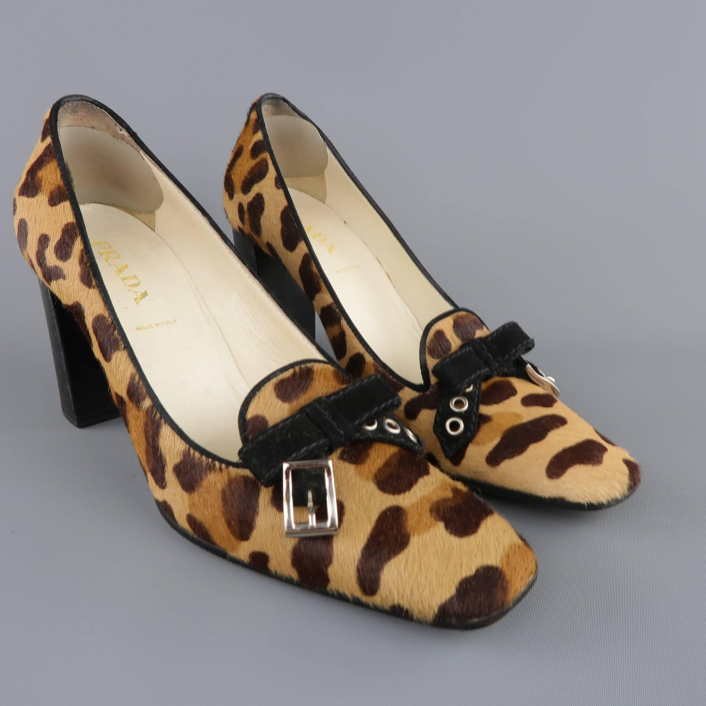 PRADA pumps come in tan leopard cheetah print ponyhair leather and feature a laofer toe line with black piping, squared off pointed toe with tied belt buckle bow, and chunky stacked heel. Wear throughout leather. As-Is. With box. Made in Italy.

