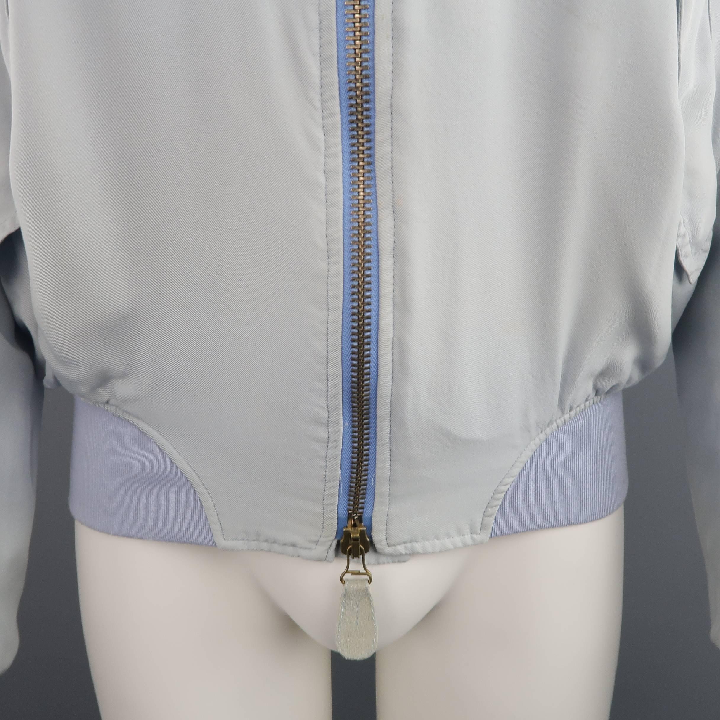 Vintage GAULTIER2 by JEAN PAUL GAULTIER MA-1 style bomber jacket comes in light weight powder blue silk twill and features a double zip front with suede tabs, slanted snap flap pockets, and ribbed knit cuffs, waistband, and baseball collar. Minor