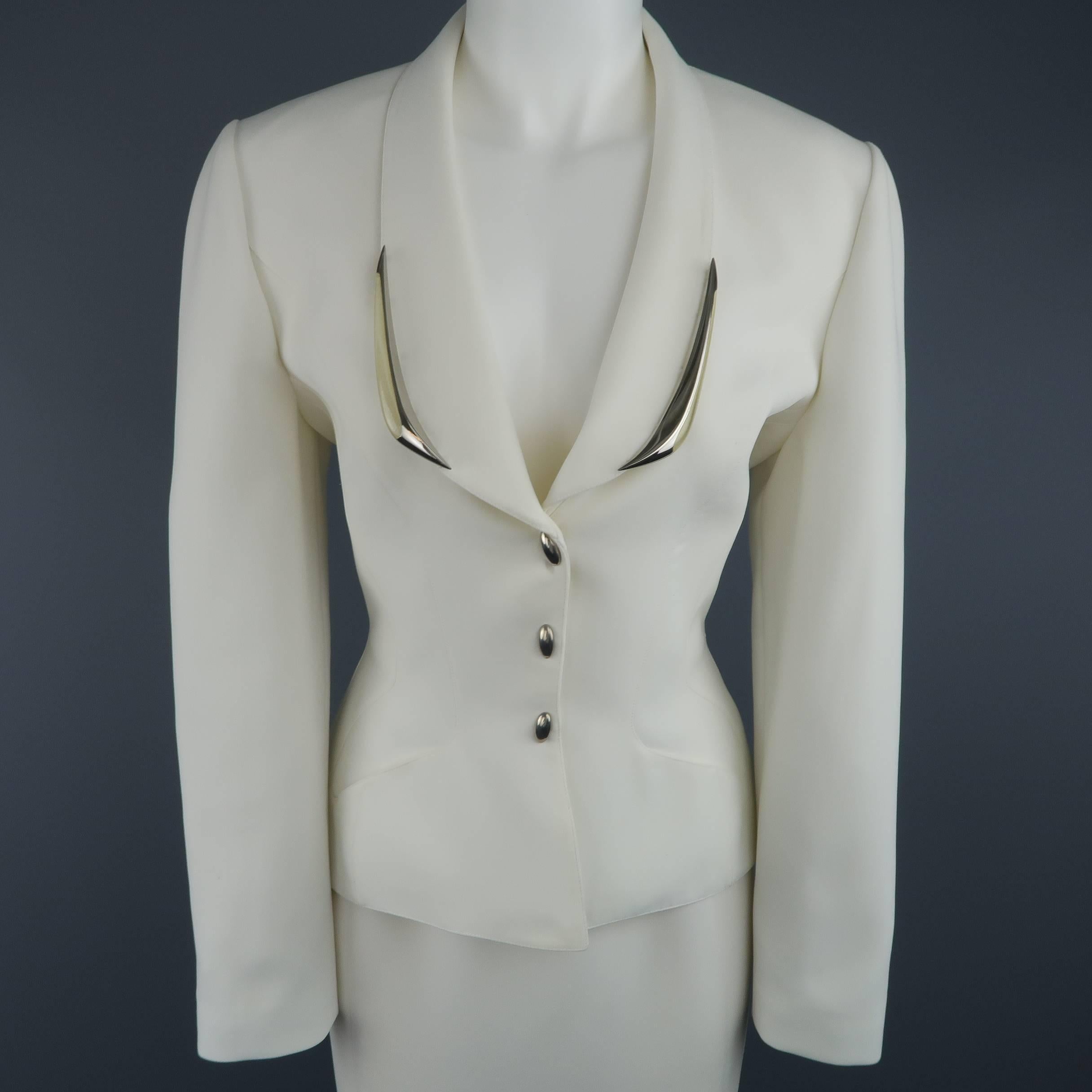 This fabulous early 1990's THIERRY MUGLER skirt suit comes in a light cream structured crepe material and includes a cinched waist, cropped jacket with silver and clear enamel embellished shawl collar and round stud snap closure with matching pencil