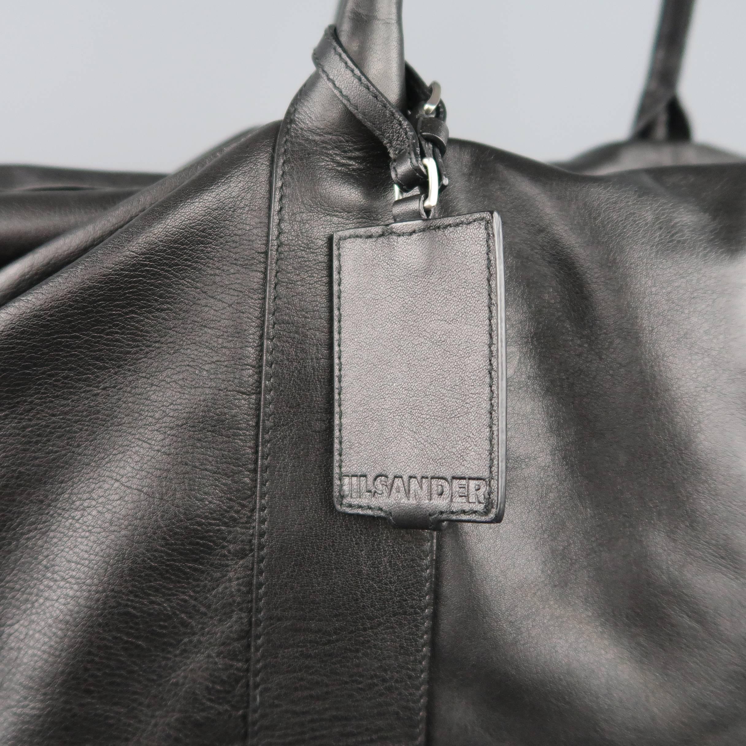 JIL SANDER weekender travel bag comes in soft black leather and features double covered top handles, embossed luggage tag, and expandable top panel with silver tone zip closure. Minor wear on leather.
 
Good Pre-Owned Condition.
 
Measurements:
