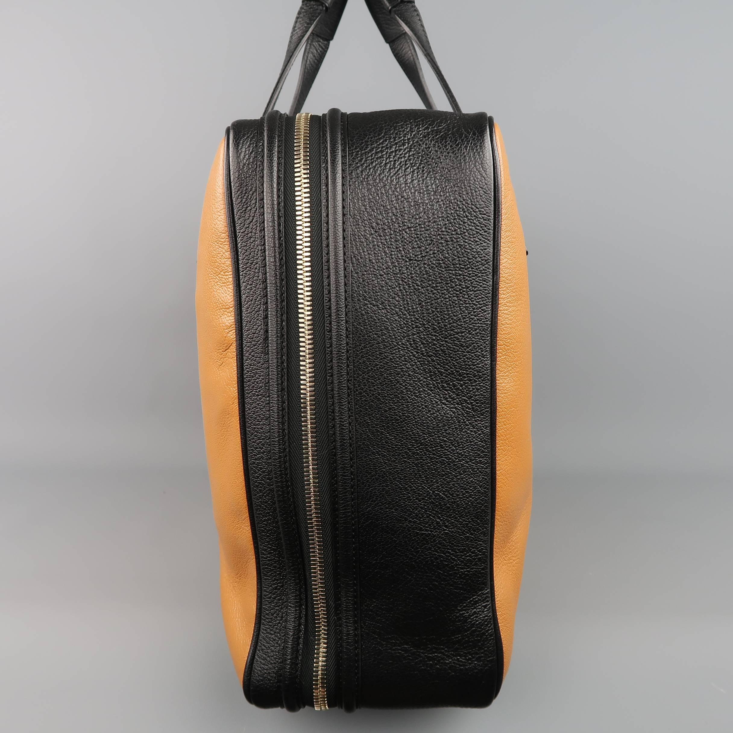 Large Tom Ford travel briefcase comes in tan and black pebbled leather and features double T line top handles with wood accents, light gold tone double zip top closure, lock with leather cover, key clochette, exterior embossed card holder, and