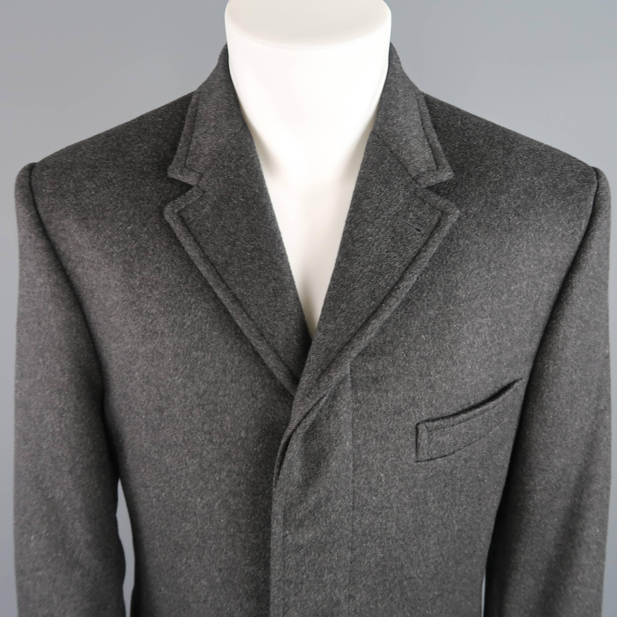 THOM BROWNE car coat comes in a charcoal gray brushed cashmere and features a classic notch lapel, three button closure with stripe lined hidden placket, flap pockets with stripe seamed trim, functional button cuffs, back tab, and nailhead lining.