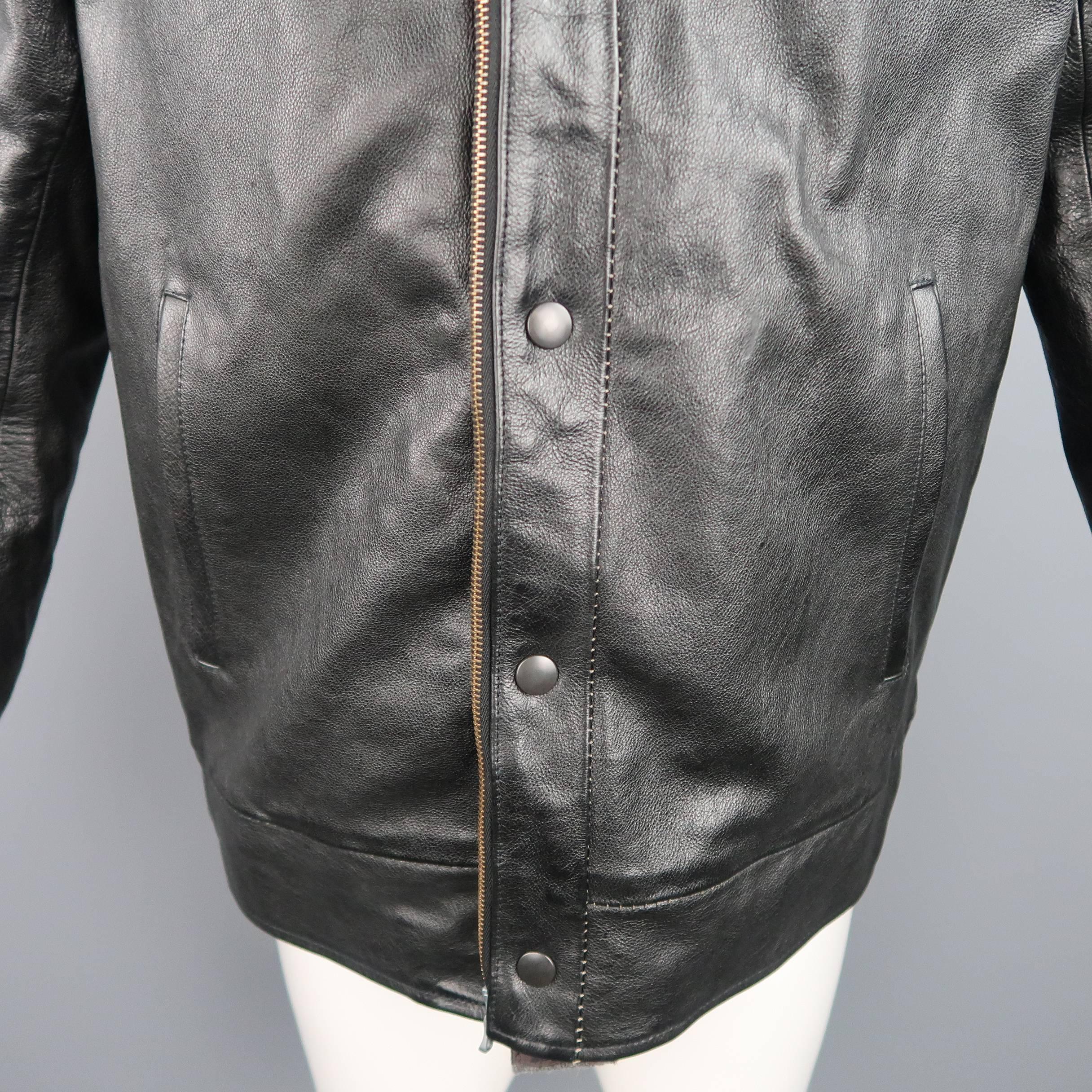 This 08SIRCUS by Kiminori Morishita bomber jacket comes in a textured black leather and features a high collar hood, raglan sleeves with contrast stitches and tab cuffs, slit pockets, snap closure, and gray wool knit detachable zip off liner. Made