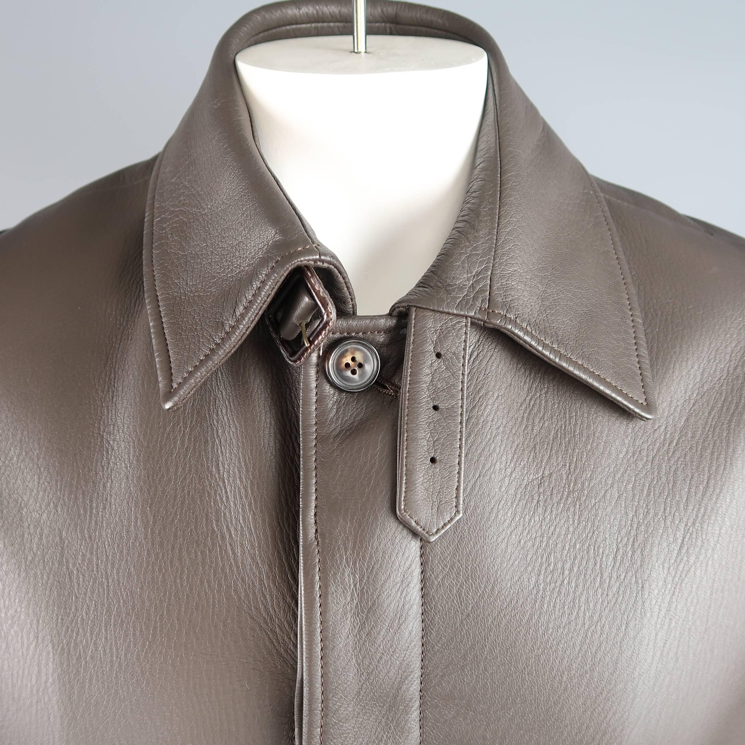PAUL STUART car coat comes in a supple dark taupe textured leather and features a classic pointed collar with buckle tab, hidden placket button front, slanted pockets, belted cuffs, and silk satin liner. Made in France.
 
Excellent Pre-Owned
