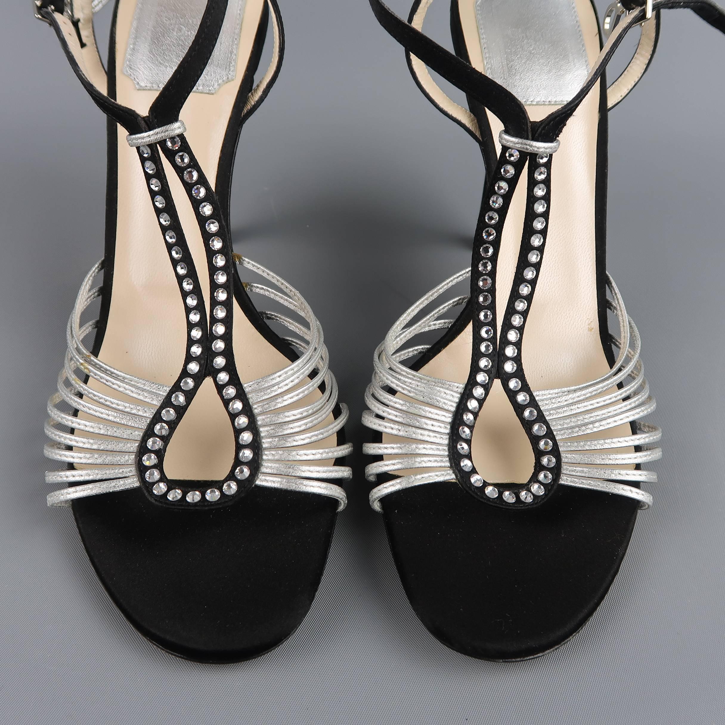 These fabulous CHRISTIAN DIOR evening sandals feature a black silk satin hoop T strap with rhinestones, covered stiletto heel, and metallic silver skinny strap details. Discolorations on silver strap and scuff on heel shown in detail shots. As-Is.