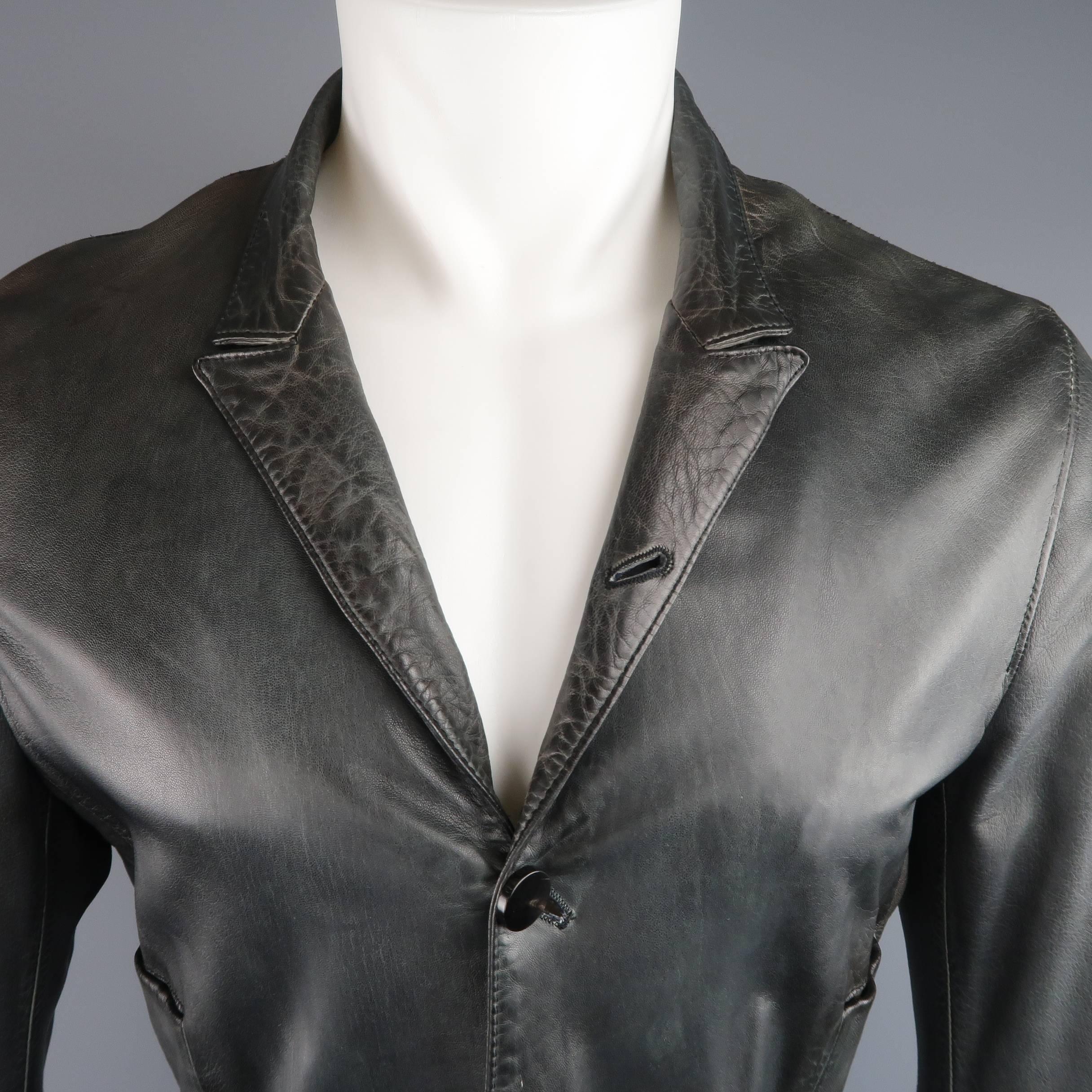 UN SOLO MONDO jacket comes in a smooth charcoal leather with unique distressed qualities throughout and features a peak lapel, half hidden, four button front, slit pockets, side belts, and double vented back. Made in Italy.
 
Good Pre-Owned