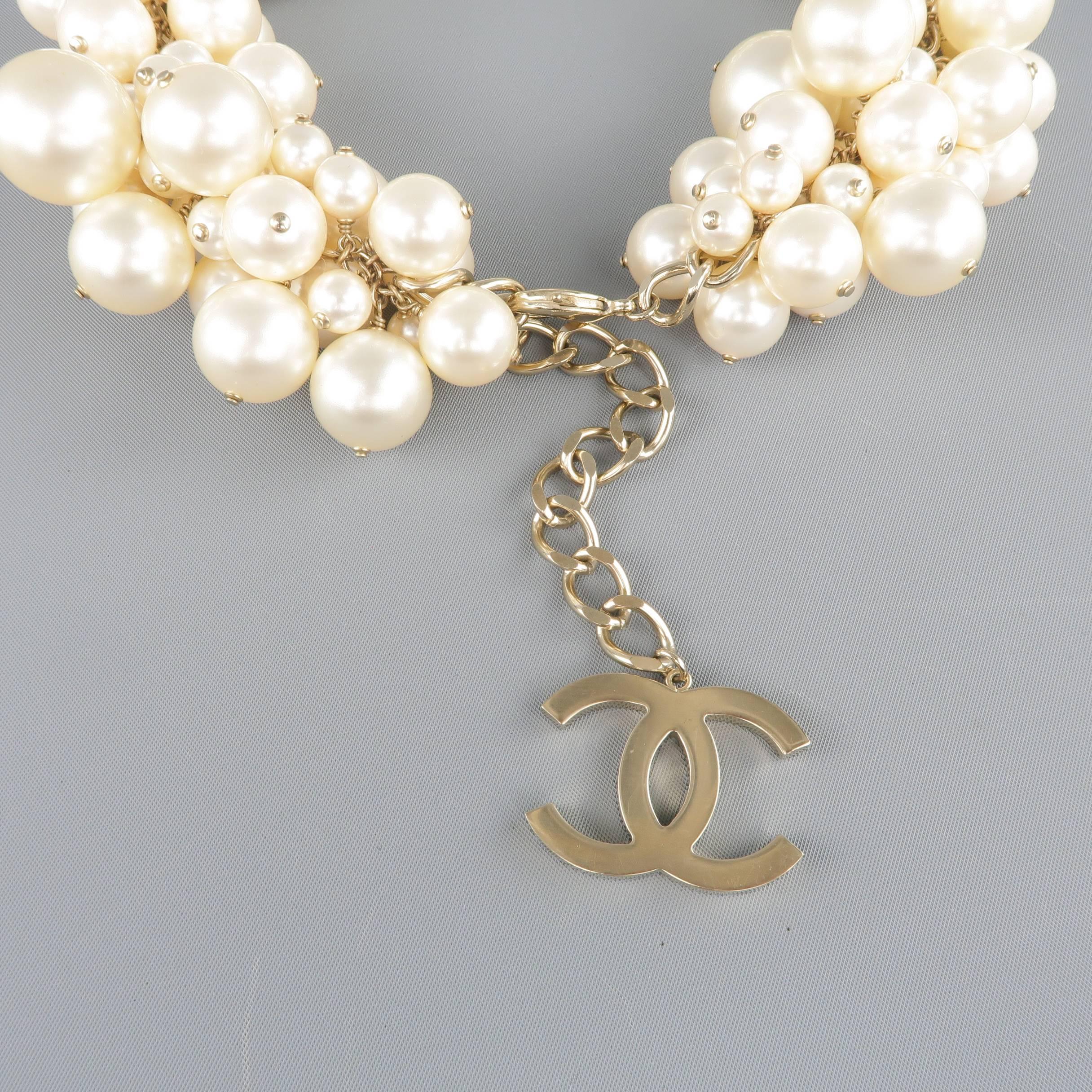 Iconic Chanel Spring Summer 2013 Collection runway necklace features a band of clustered oversized faux pearls on a light gold tone chain with CC logo charm. Scuff on pearl shown in detail shot. Otherwise excellent condition.  As-is. Includes