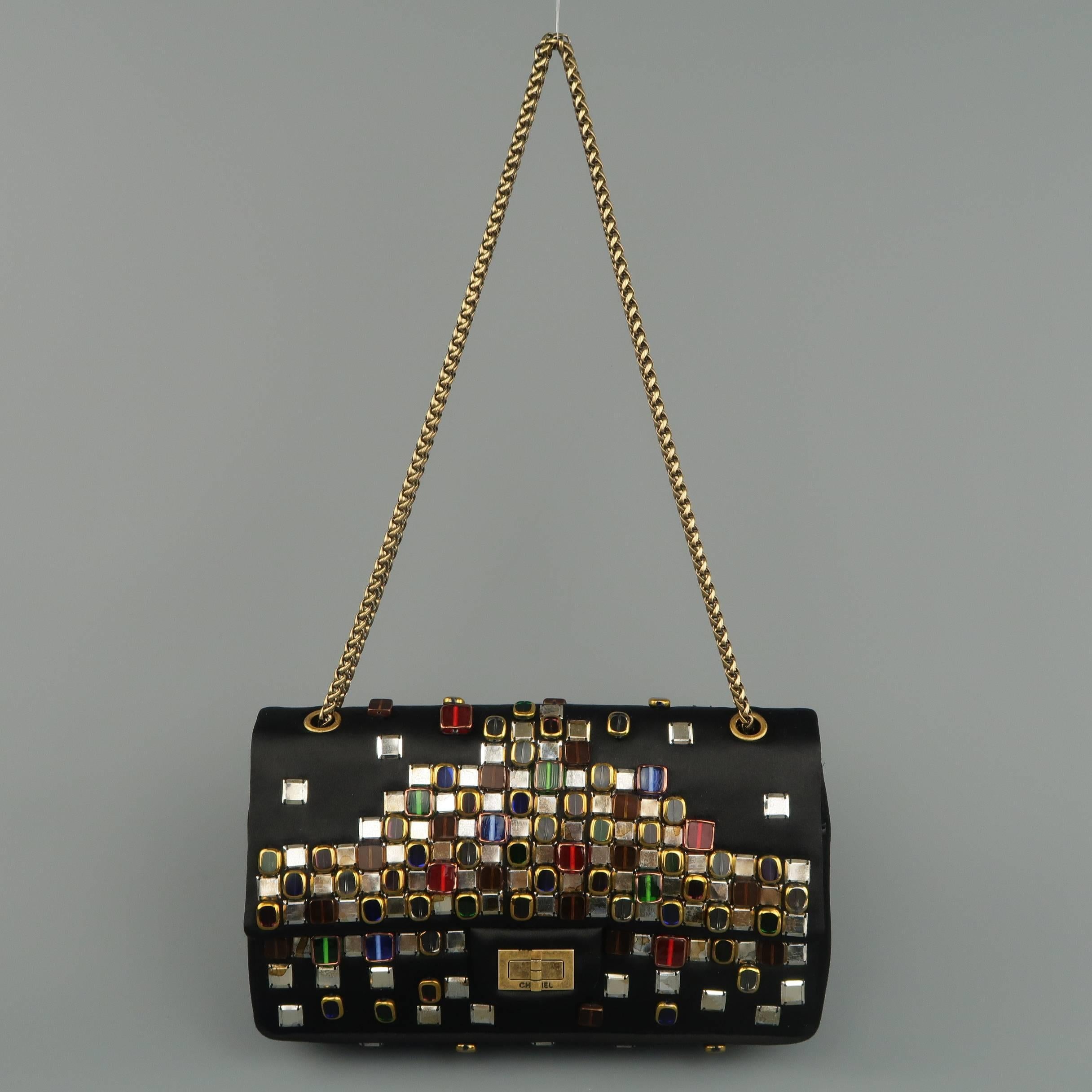 Rare CHANEL Pre-Fall 2011 Collection Byzantine Reissue shoulder bag comes in black silk satin and features gold and silver tone with various gemstone beaded studs, antiqued gold tone hardware, double chain strap, and internal pockets. Made in