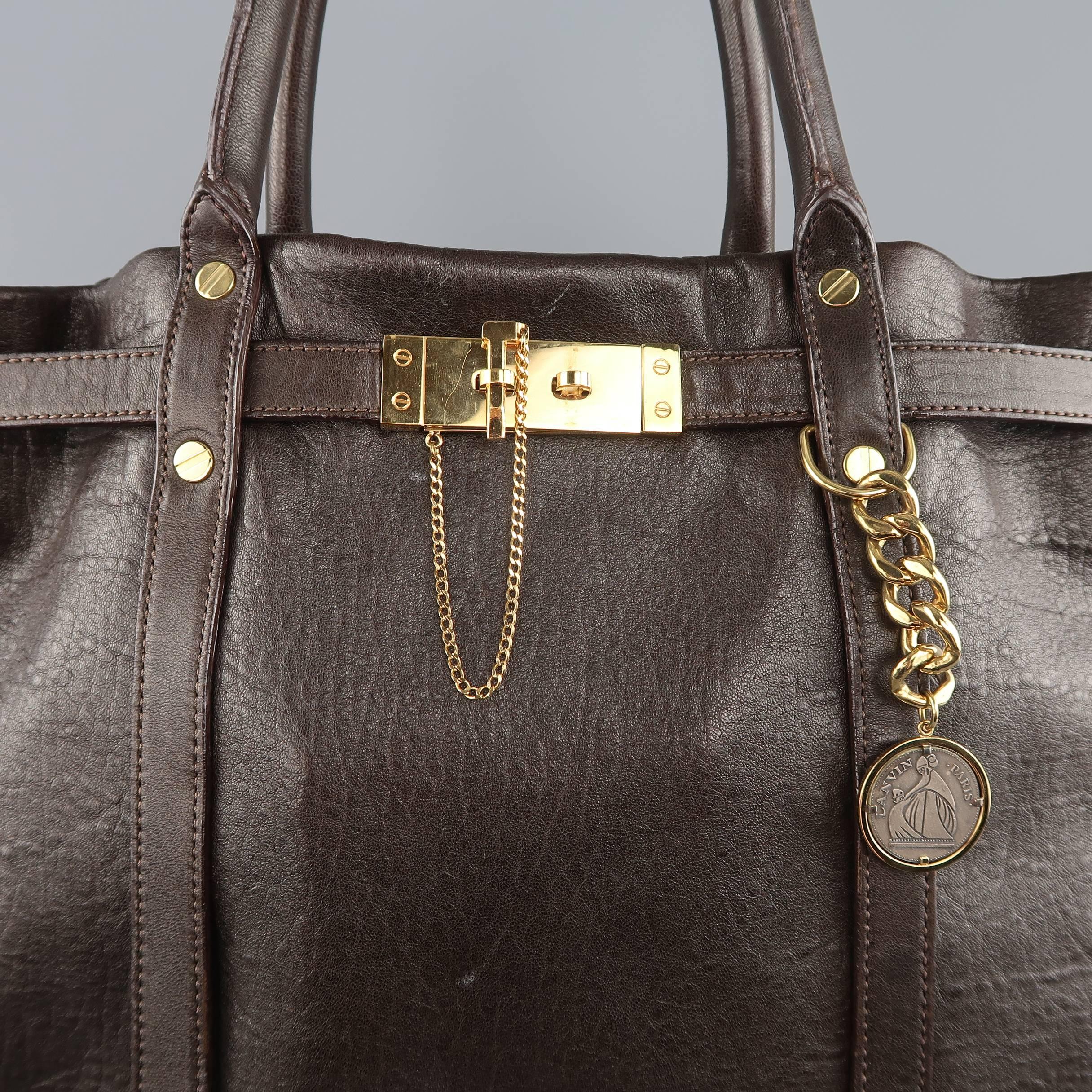 LANVIN tote bag comes in chocolate brown textured leather and features gold tone screw hardware, double top covered handles and top belt with lock detail. Wear throughout. Missing pouch. As-Is.  Made in France.
 
Good Pre-Owned Condition.

