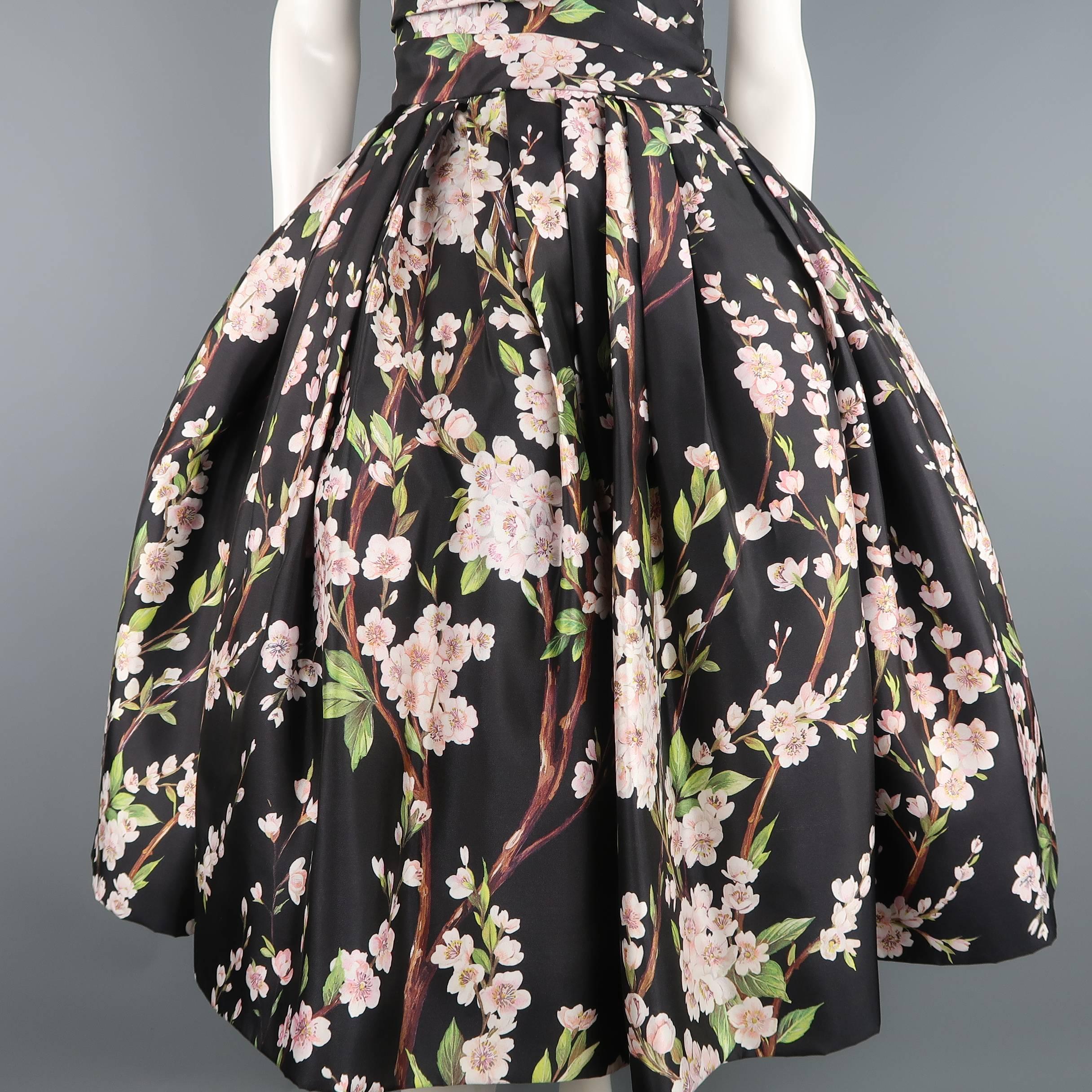 This gorgeous DOLCE & GABBANA cocktail dress comes in black silk twill with all over cherry blossom floral print and features an asymmetrical pleated fully boned bustier bodice with pointed sweetheart line and midi length circle skirt with full