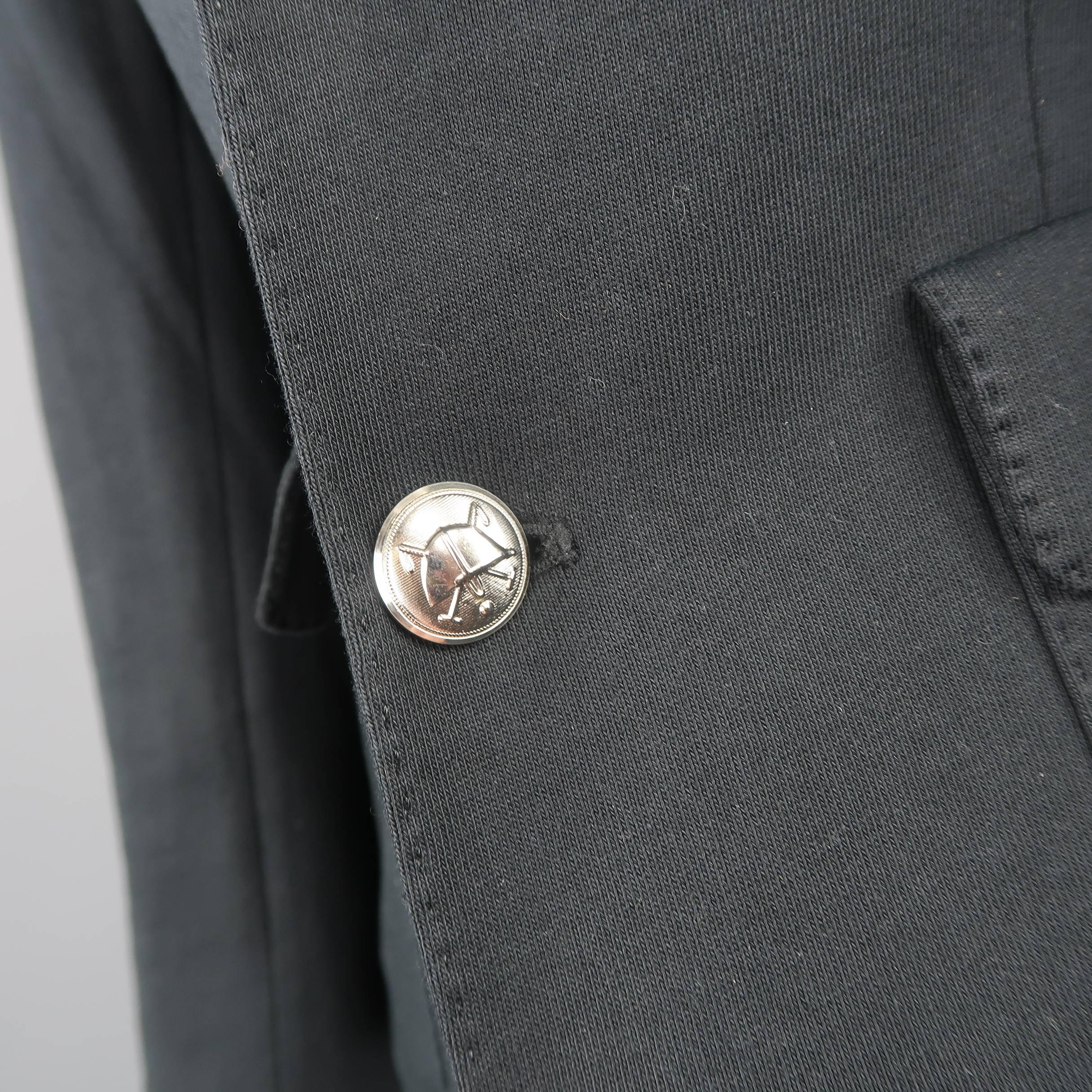 RALPH LAUREN blazer comes in a black cotton jersey and features a notch lapel with top stitching, double patch flap pockets, silver tone engraved buttons, faux button cuffs, and RL coat of arms metallic embroidered breast pocket.
 
Good Pre-Owned