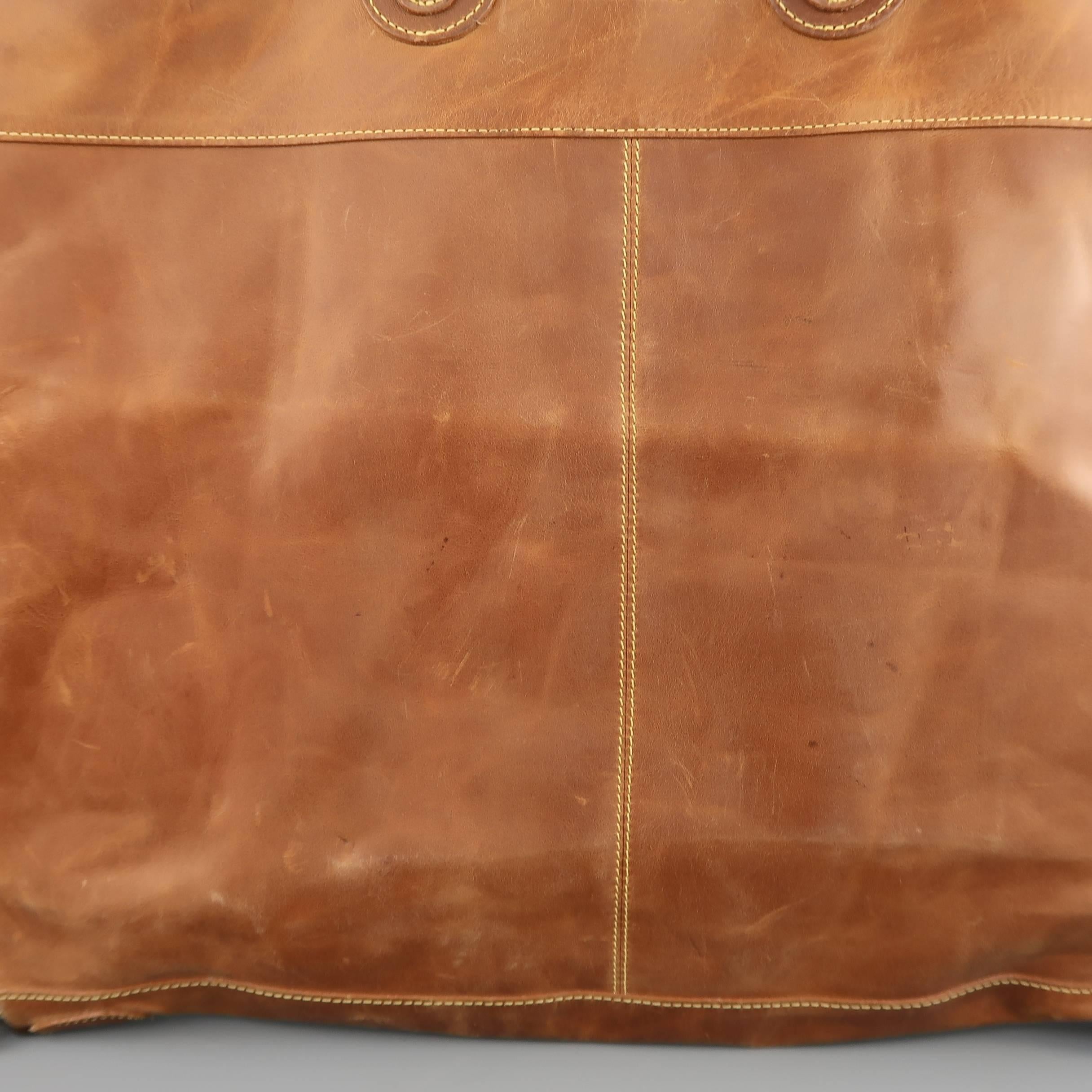 Vintage MULHOLLAND travel garment bag comes in tan leather and features double top handles with gold tone hardware, flat rectangular shape, zip around closure, embossed logo patches, and internal zip lining. Wear throughout. As-is.  Made in USA.
