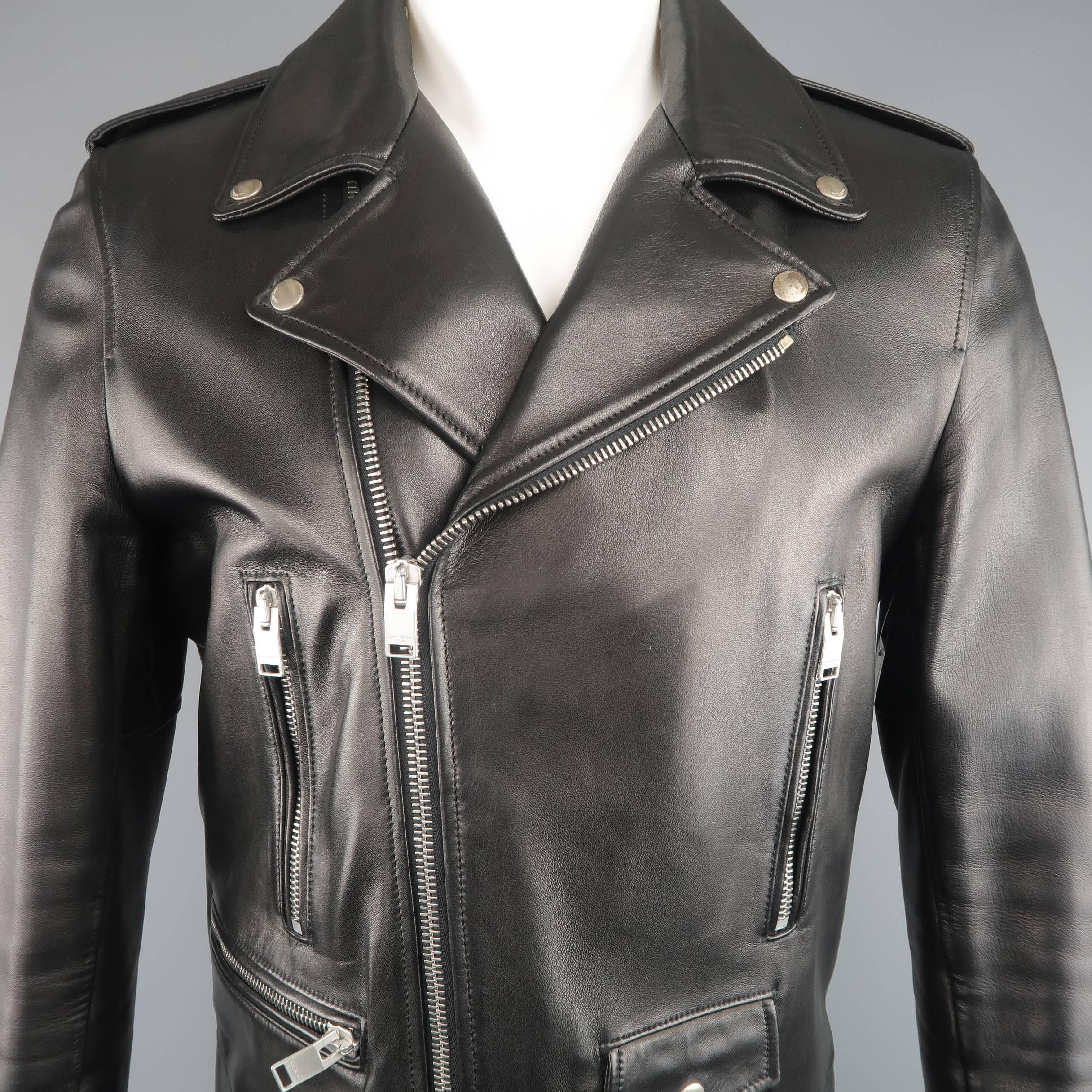 Classic SAINT LAURENT moto biker jacket by Hedi Slimane comes in smooth black lambskin leather and features a pointed collar snap down lapel, epaulets, asymmetrical zip front, zip pockets, snap belt loops, and zip cuffs. Minor wear including