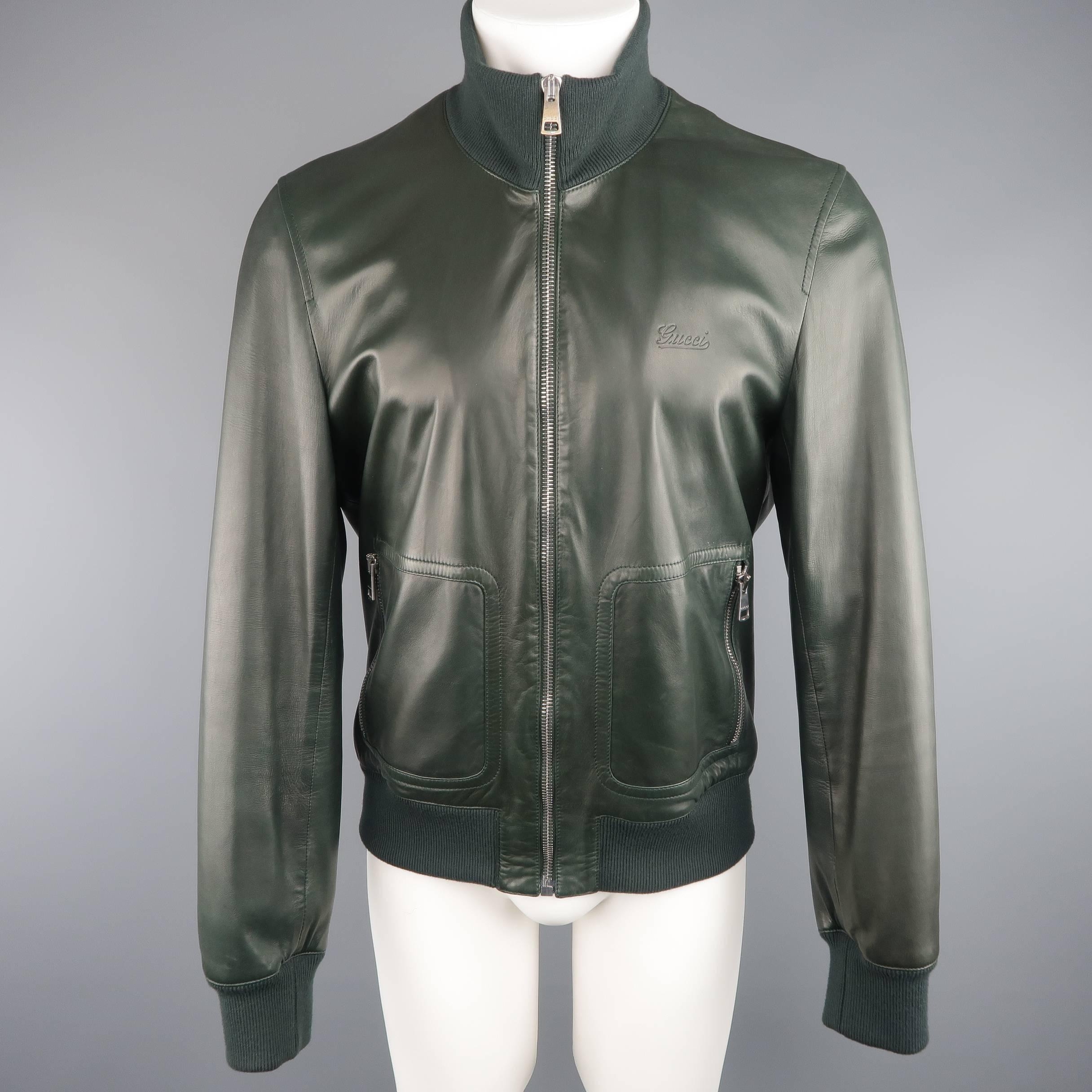 Tailored GUCCI bomber jacket comes in a rich forest green soft leather and features a high ribbed knit collar with internal stripe pattern, zip up front, double zip pockets, and logo embossed chest. Minor wear. Made in Italy.
 
Good Pre-Owned