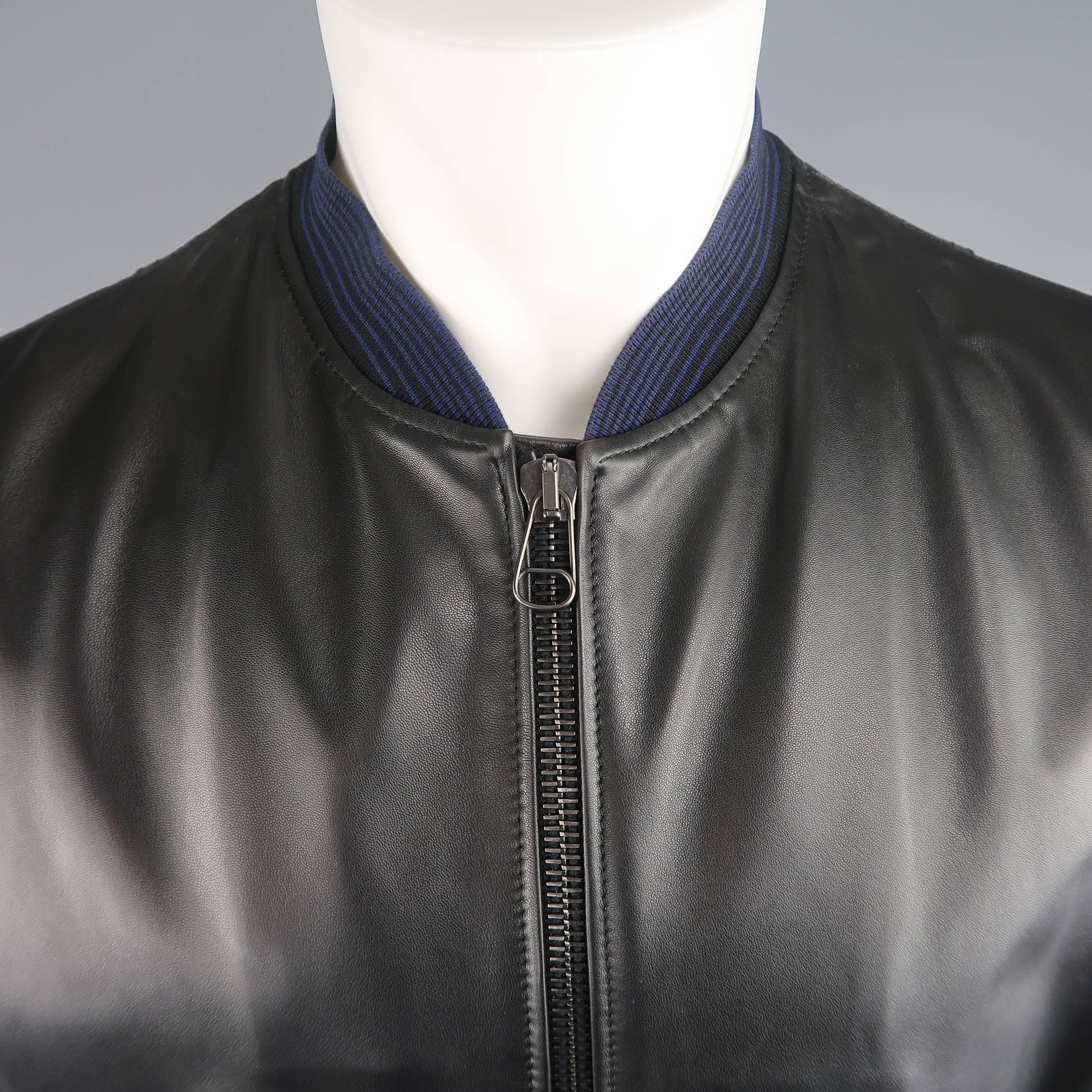 Tailored LANVIN bomber jacket comes in charcoal canvas and features a smooth black leather front panel with slanted snap pockets, zip closure, sleeve pockets, and blue striped baseball collar, cuffs, and waistband. Made in Italy.
 
Excellent