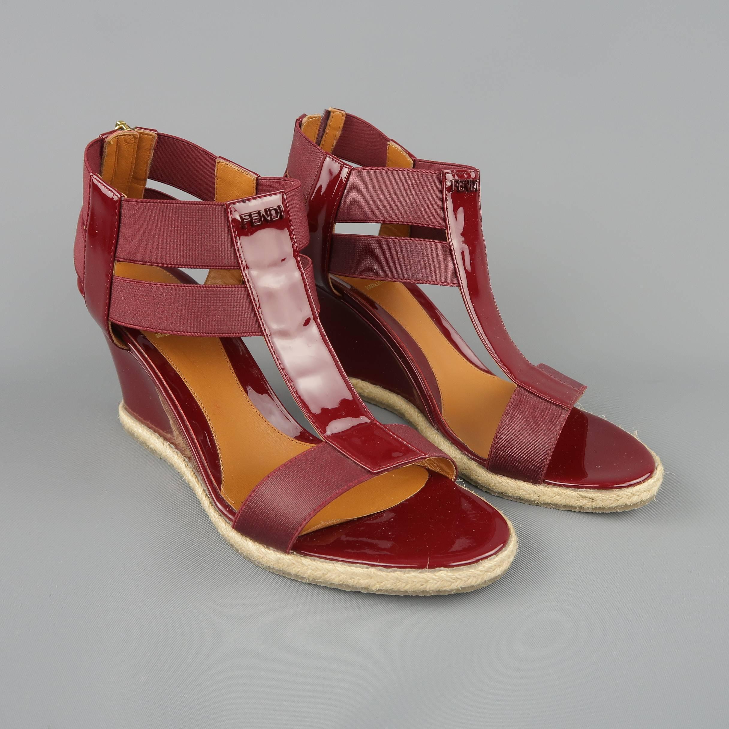 FENDI sandals come in burgundy patent leather and feature a T strap front with elastic sides, back zip, and covered wedge heel with espadrille woven trim. With box.  Made in Italy.
 
Good Pre-Owned Condition.
Marked: IT 38.5
 
Measurements:
 
Heel: