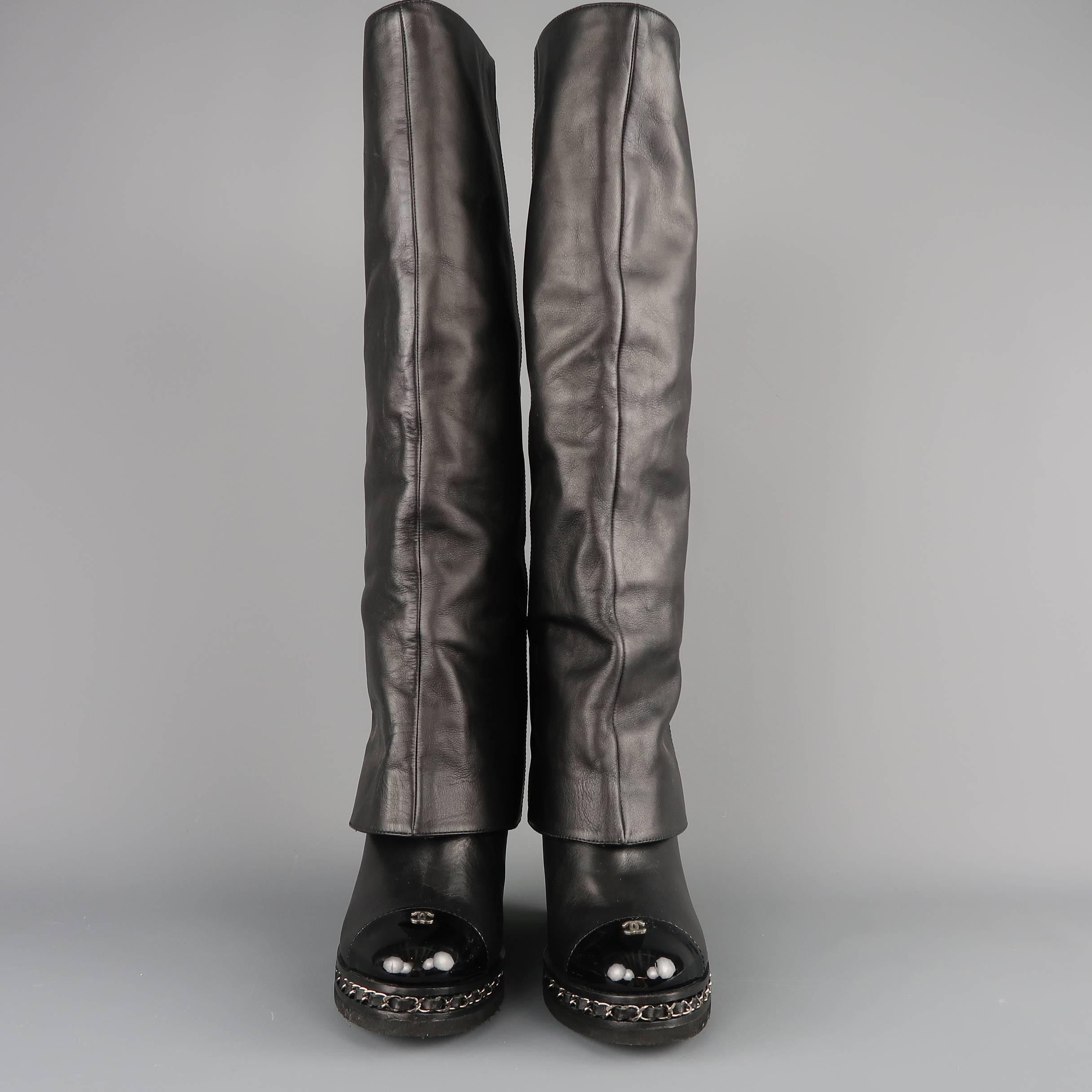 CHANEL knee high boots come in smooth black leather with a fold over shaft, patent leather cap toe with silver tone CC, and covered wedge with woven chain midsole. Vibram sole added. Made in Italy.  Retail: $2150.00

Good Pre-Owned