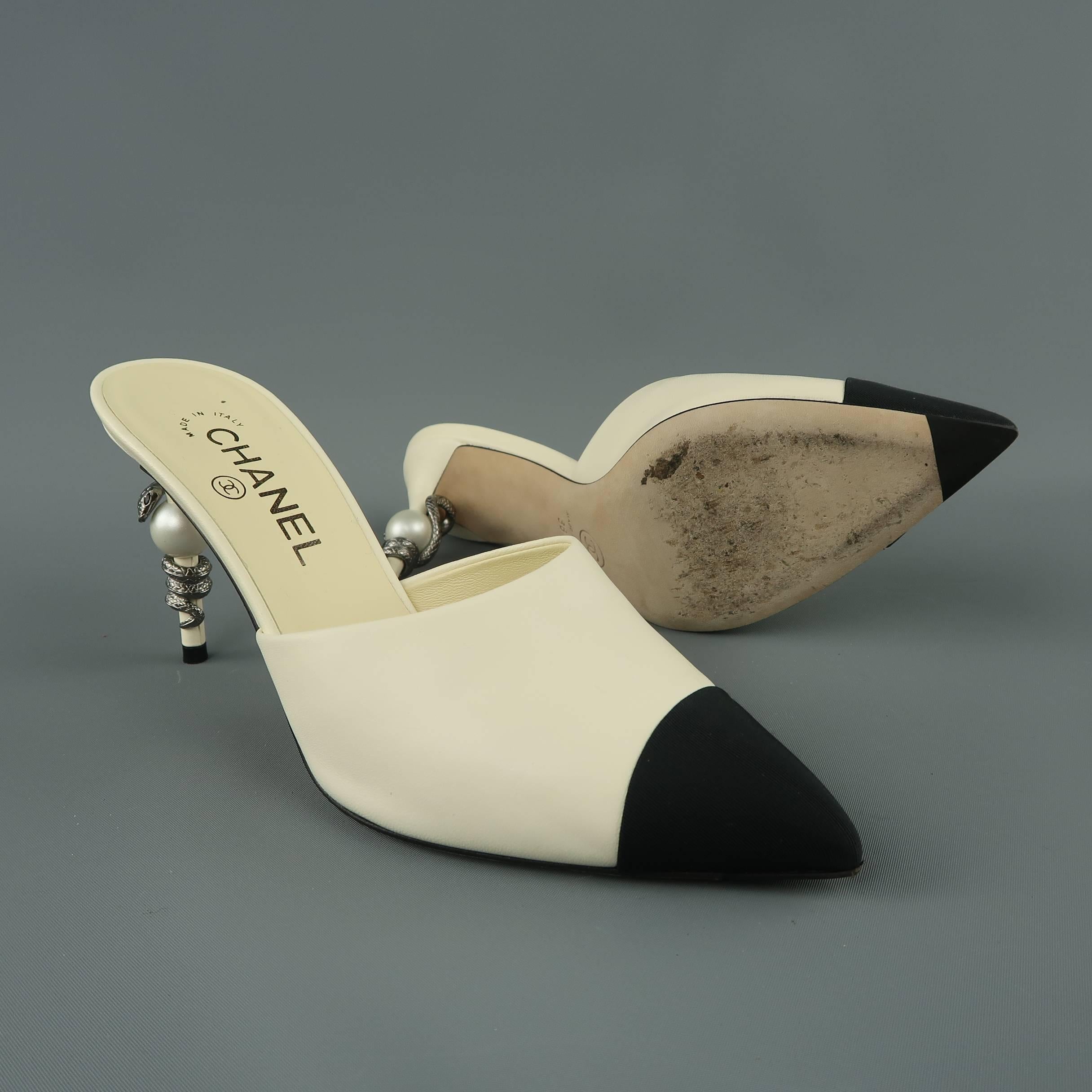 CHANEL mules comes in smooth cream leather with a black pointed grosgrain toe cap and feature a covered stiletto heel with faux pearl and silver tone, crystal eye snake coiled around it. Circa 2016. Made in Italy.
 
Excellent Pre-Owned