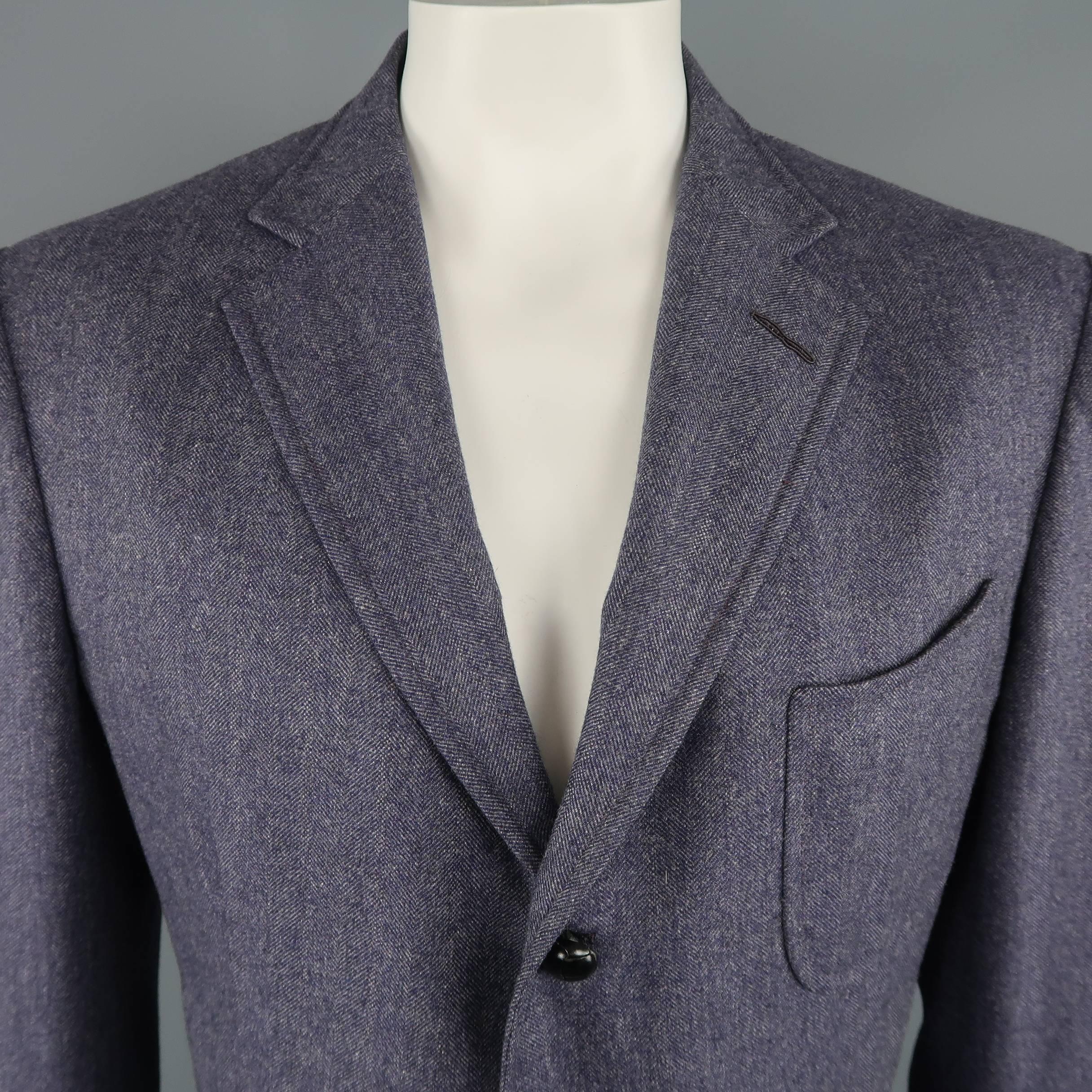 Tom Ford sport coat comes in light indigo purple wool cashmere blend herringbone fabric with a notch lapel, triple patch pockets, three button closure with black knotted buttons, and functional button cuffs. Discoloration on right sleeve. As-is.