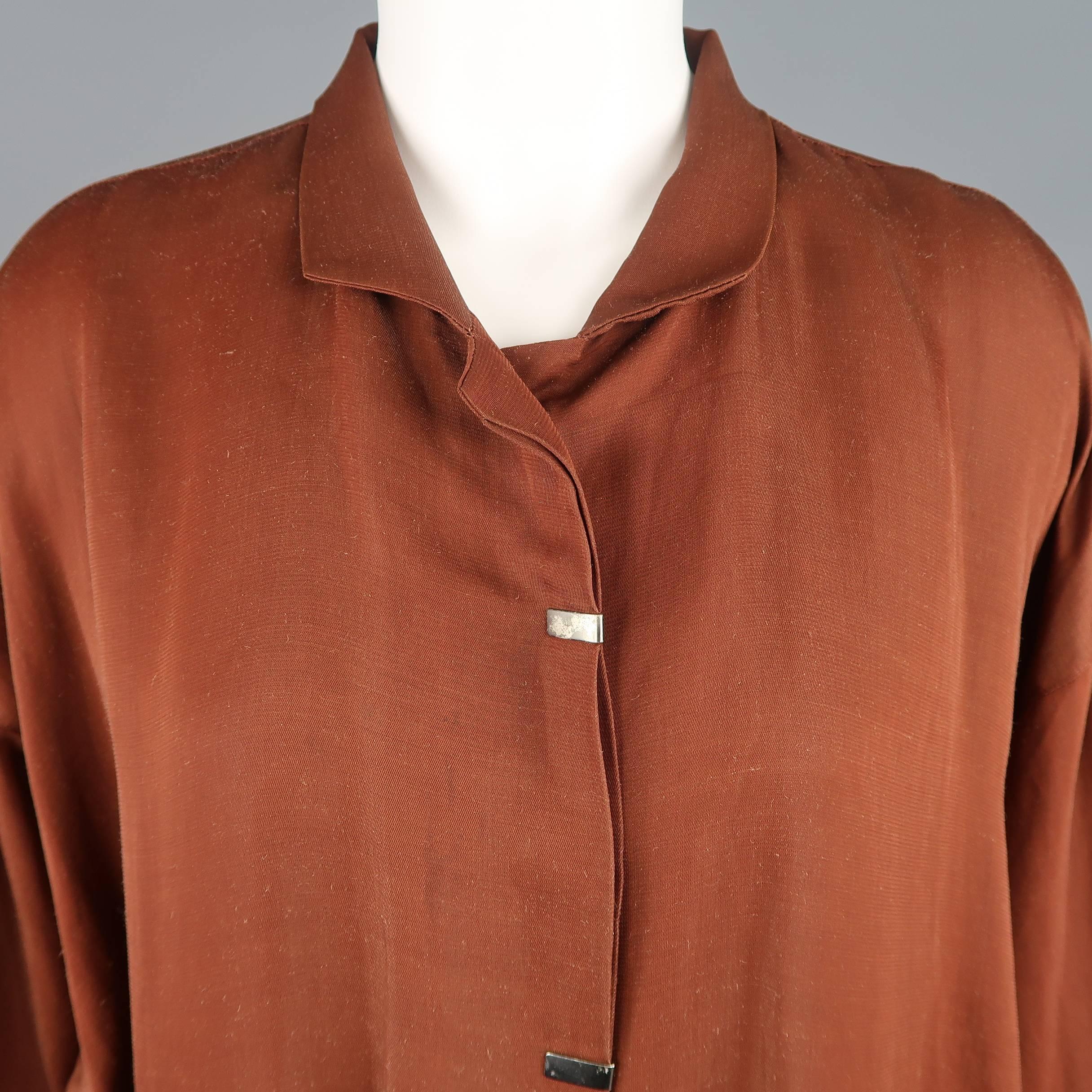 Vintage Issey Miyake oversized jacket comes in light weight rust brown fabric with a small collar, hidden placket button closure with silver tone metal embellishments, slit pockets, and weighted sides. Wear throughout. As-is. Made in Japan.
 
Fair