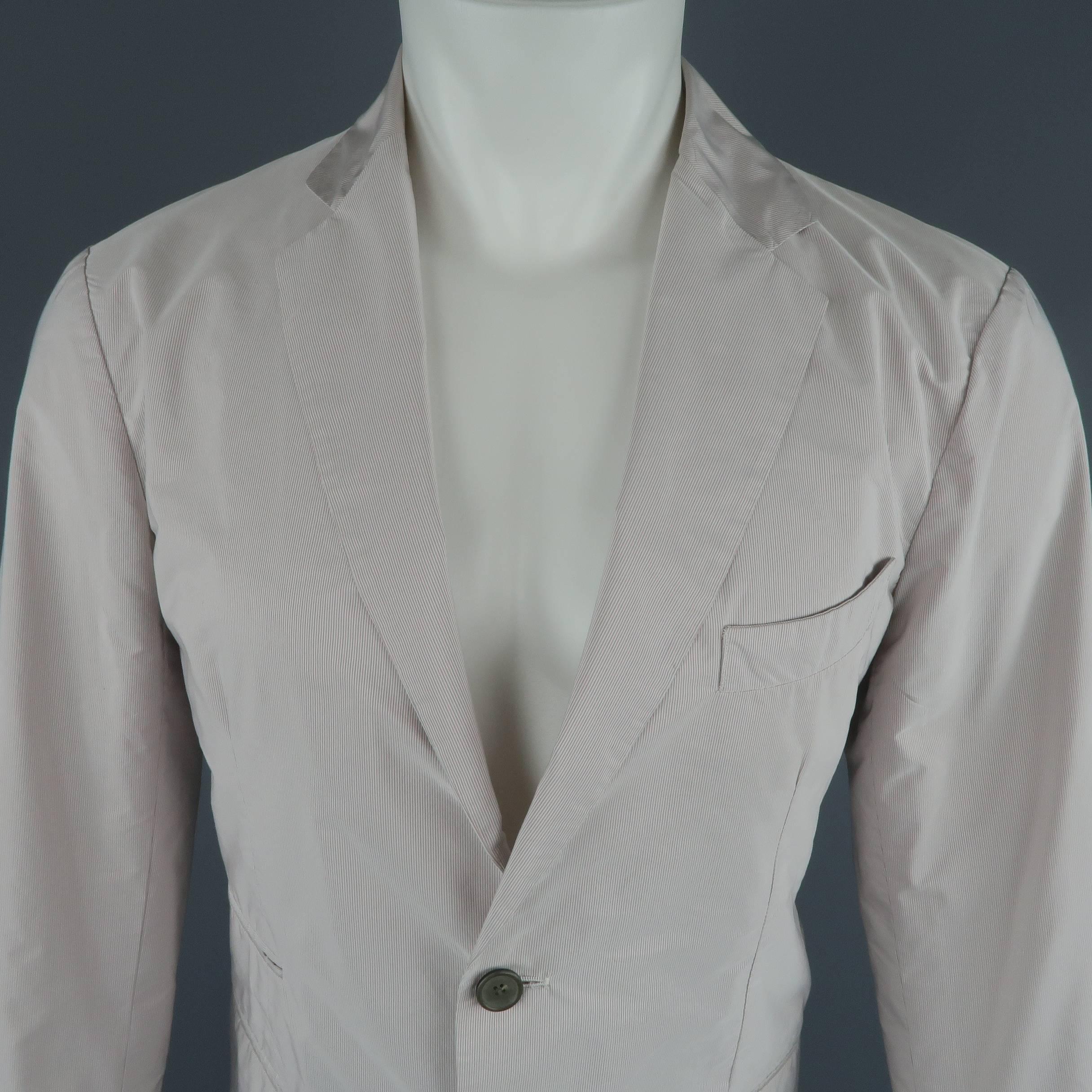 Jil Sander sport coat comes in a light weight beige sporty polyester taffeta material with very faint pink and gray micro stripe pattern, notch lapel, two button front , and slit pockets. Made in Italy.
 
Good Pre-Owned Condition.
Marked: IT 52
