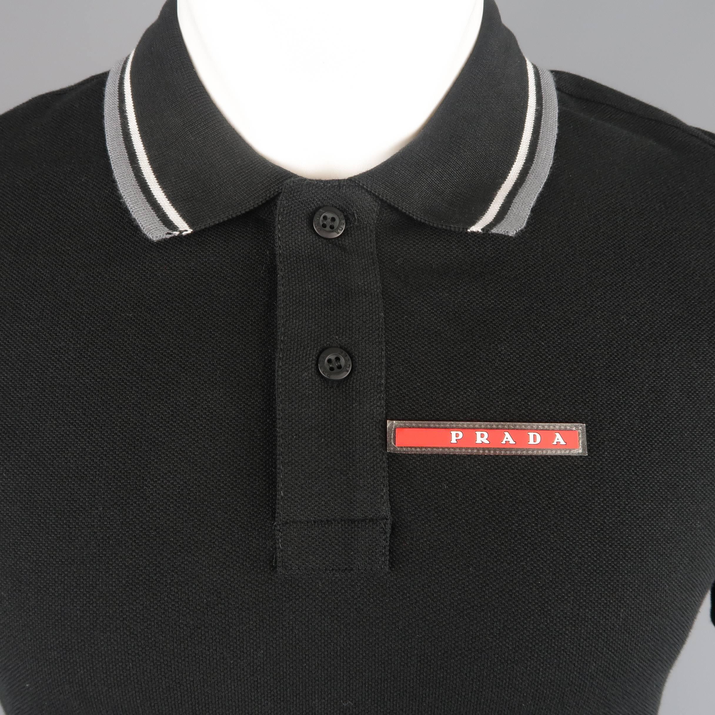Classic PRADA polo comes in black cotton pique with gray striped trim and red rubber logo tab.
 
New with Tags.
Marked: M
 
Measurements:
 
Shoulder: 17 in.
Chest: 38 in.
Sleeve: 8 in.
Length: 28 in.